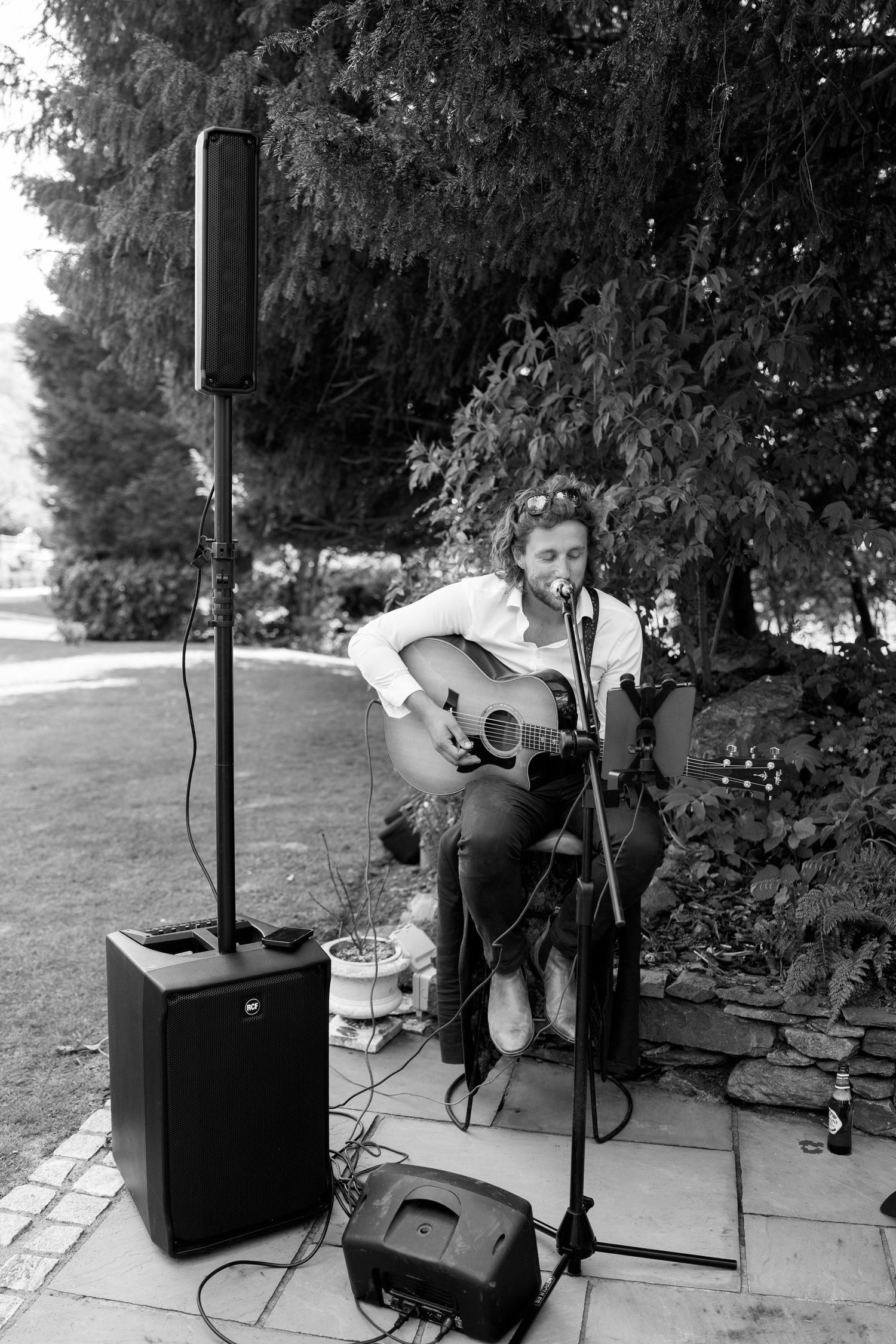 A musician performs with an acoustic guitar and microphone setup at an outdoor event.