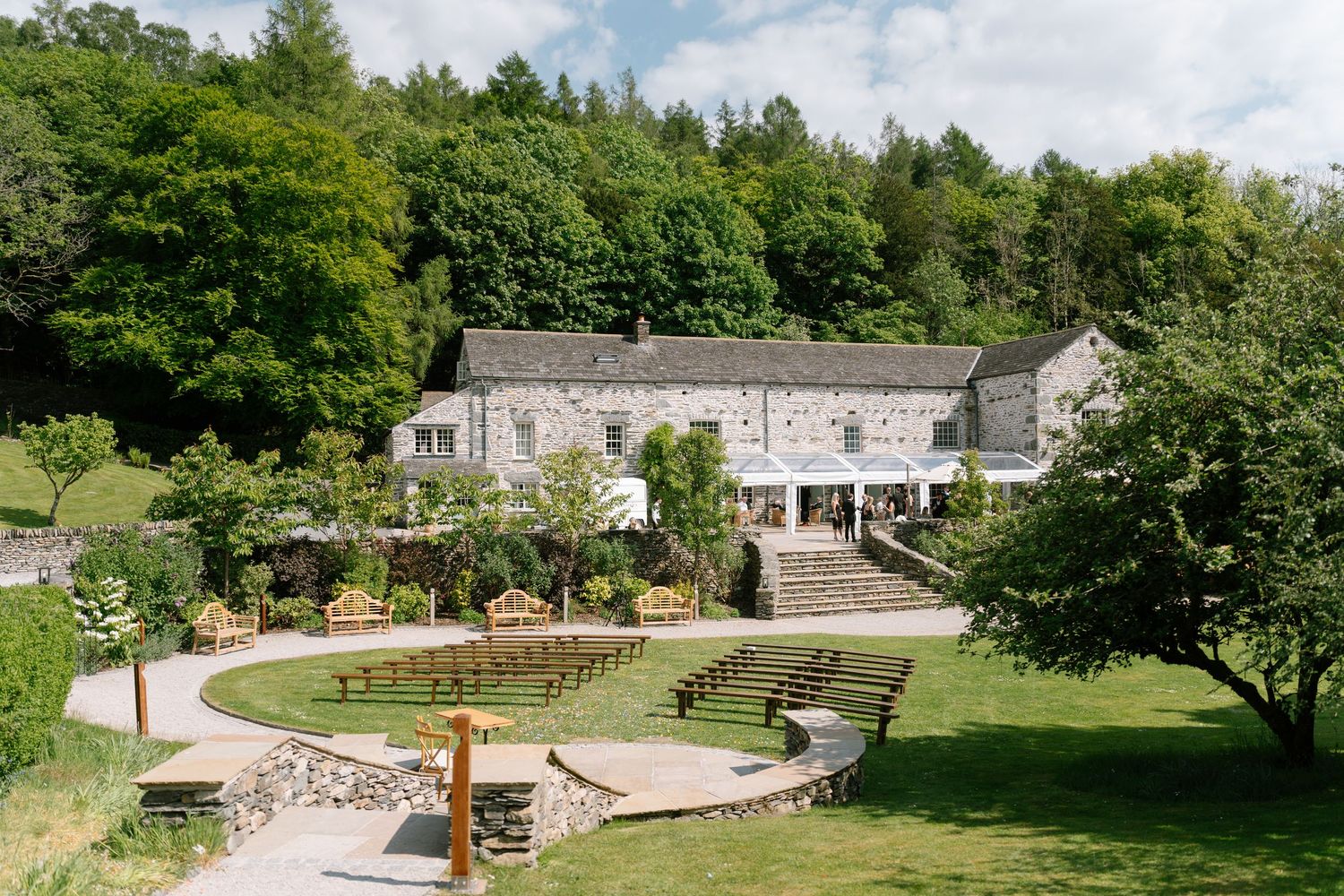 Panoramic view of a stone amphitheater and garden venue surrounded by lush green trees.