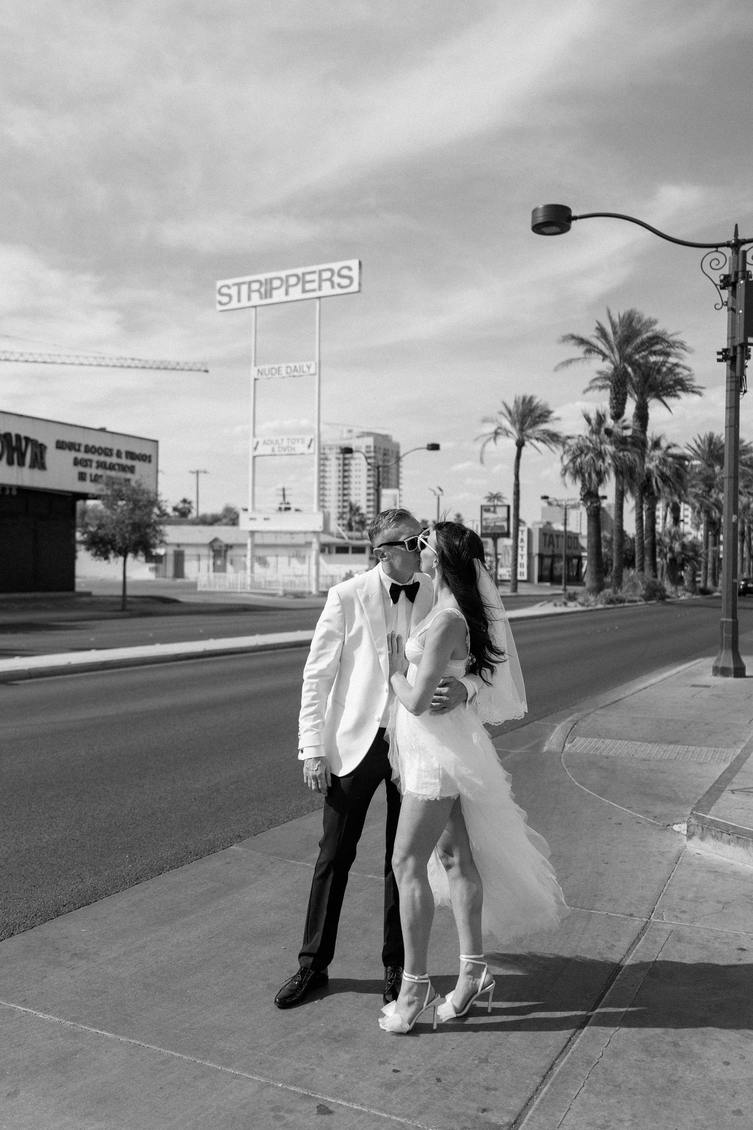 Black and white photo of newlyweds posing on a Las Vegas sidewalk.