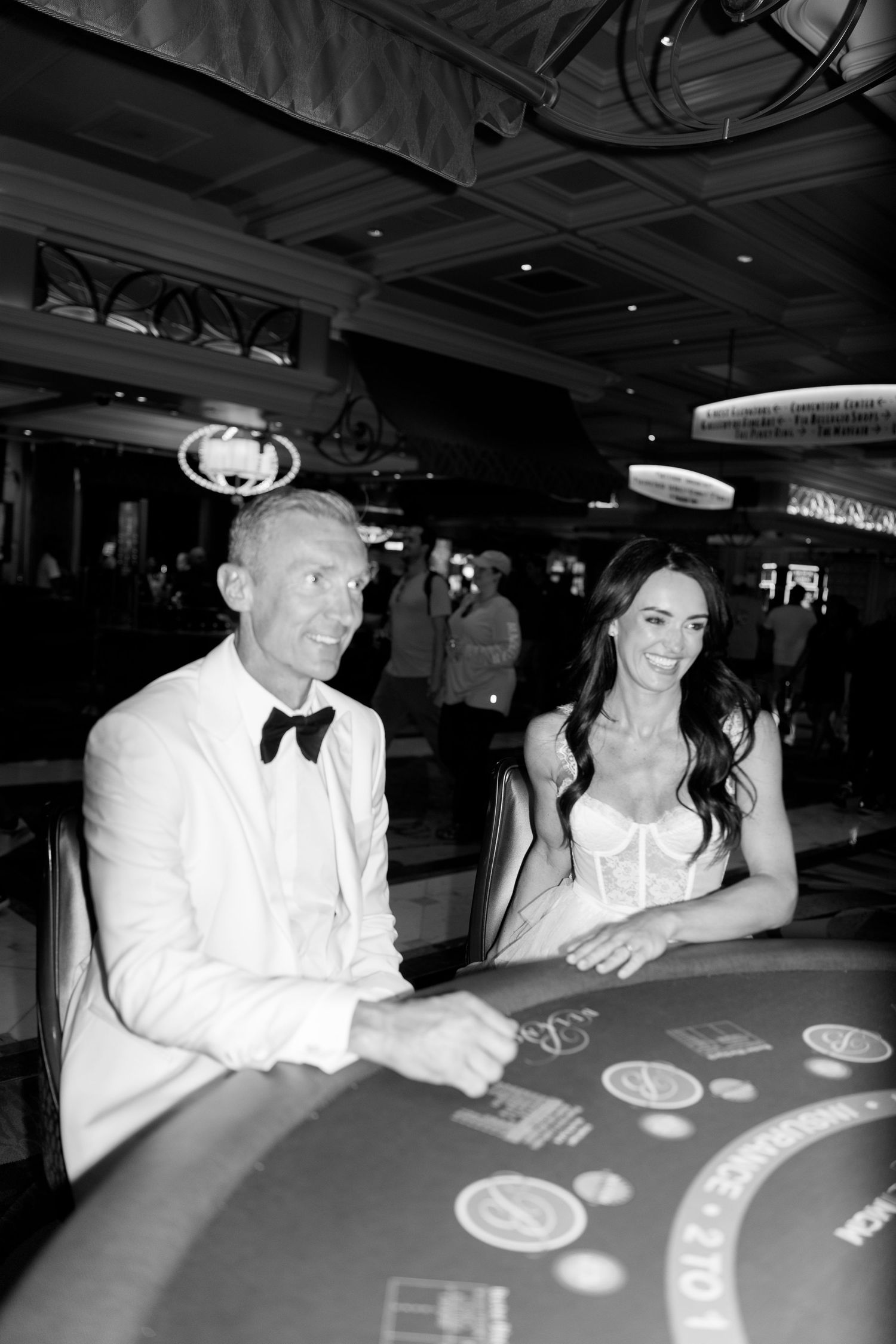 Wedding couple playing blackjack at a casino table in formal attire.