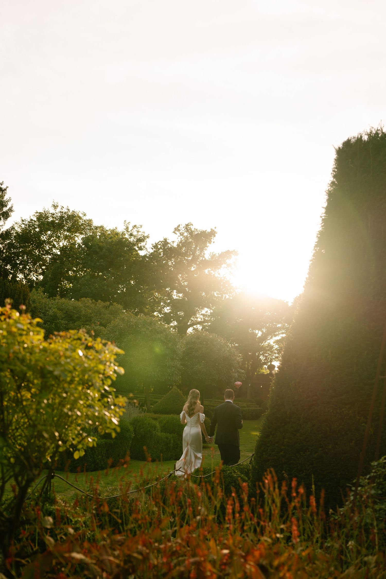 Silhouette of couple walking through garden at sunset.