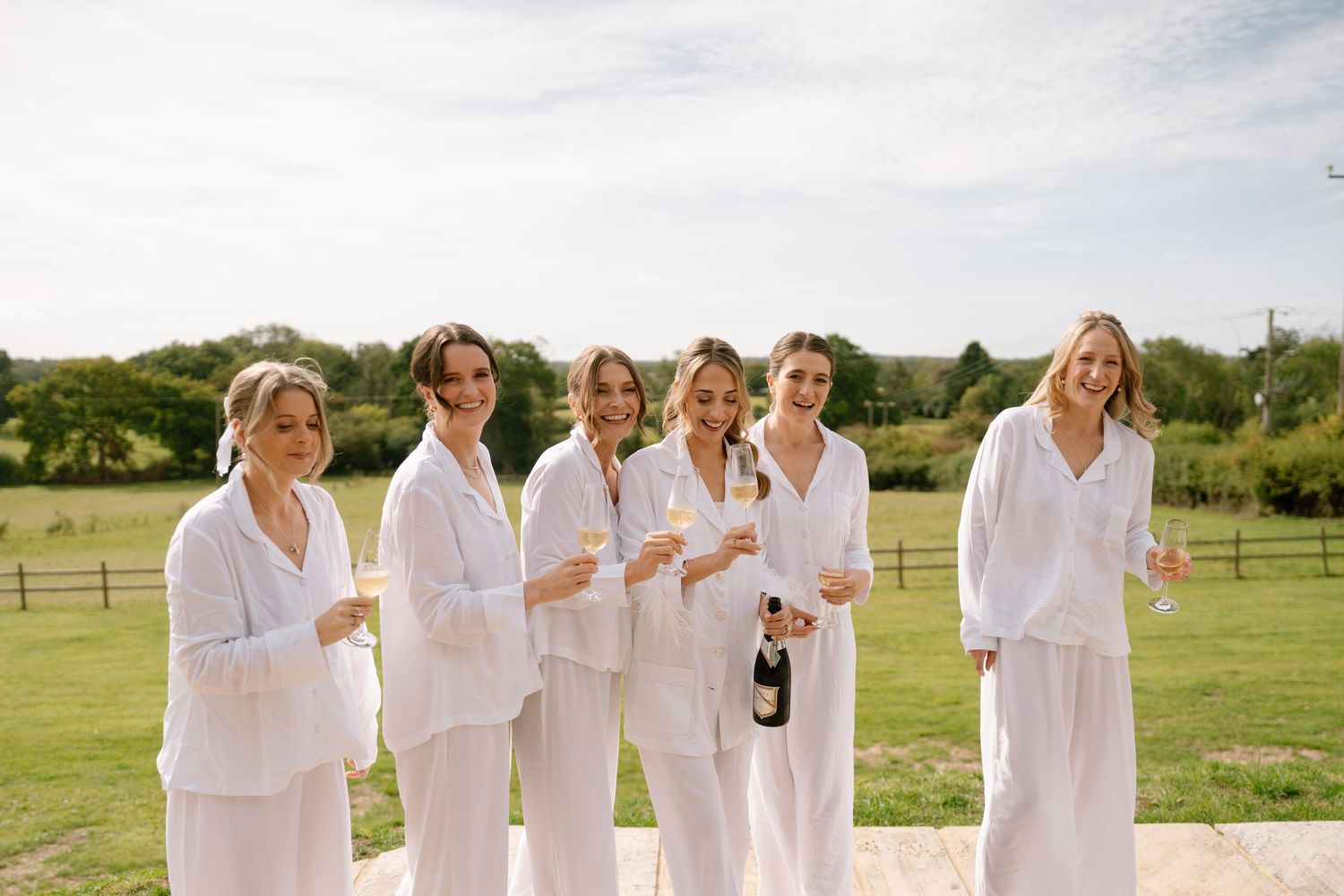 A group in coordinated white outfits poses together on a sunny outdoor patio.