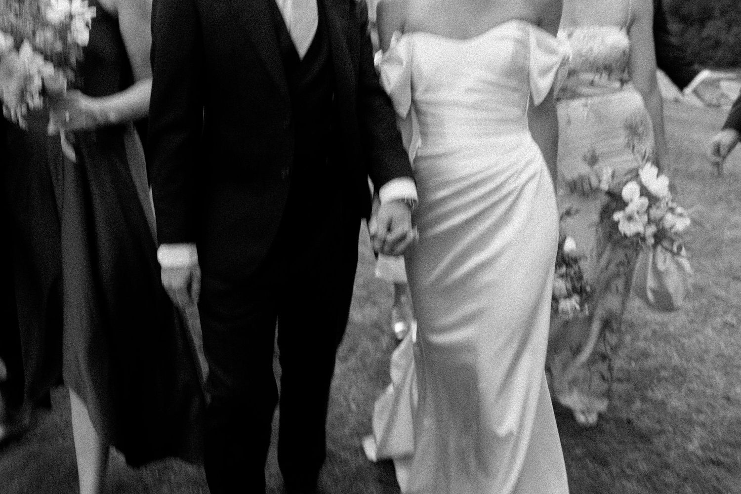 Wedding party members walking and chatting together outdoors in formal attire.