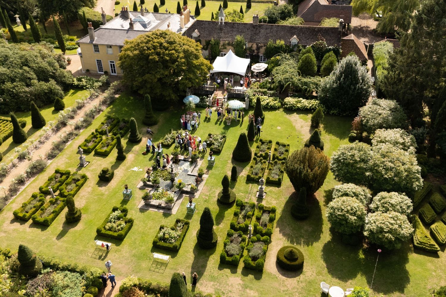 Aerial view of a formal garden with white tents and geometric landscaping patterns.