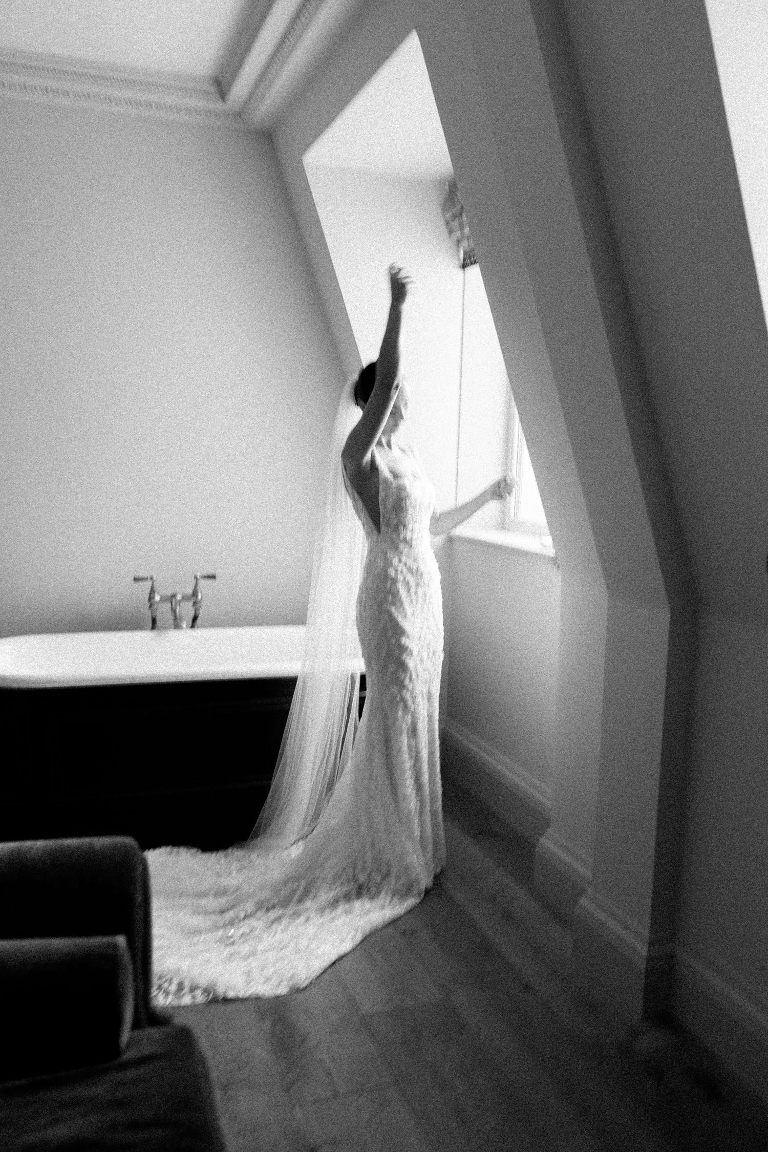 Artistic low angle shots of wedding dress train flowing across wooden floor.