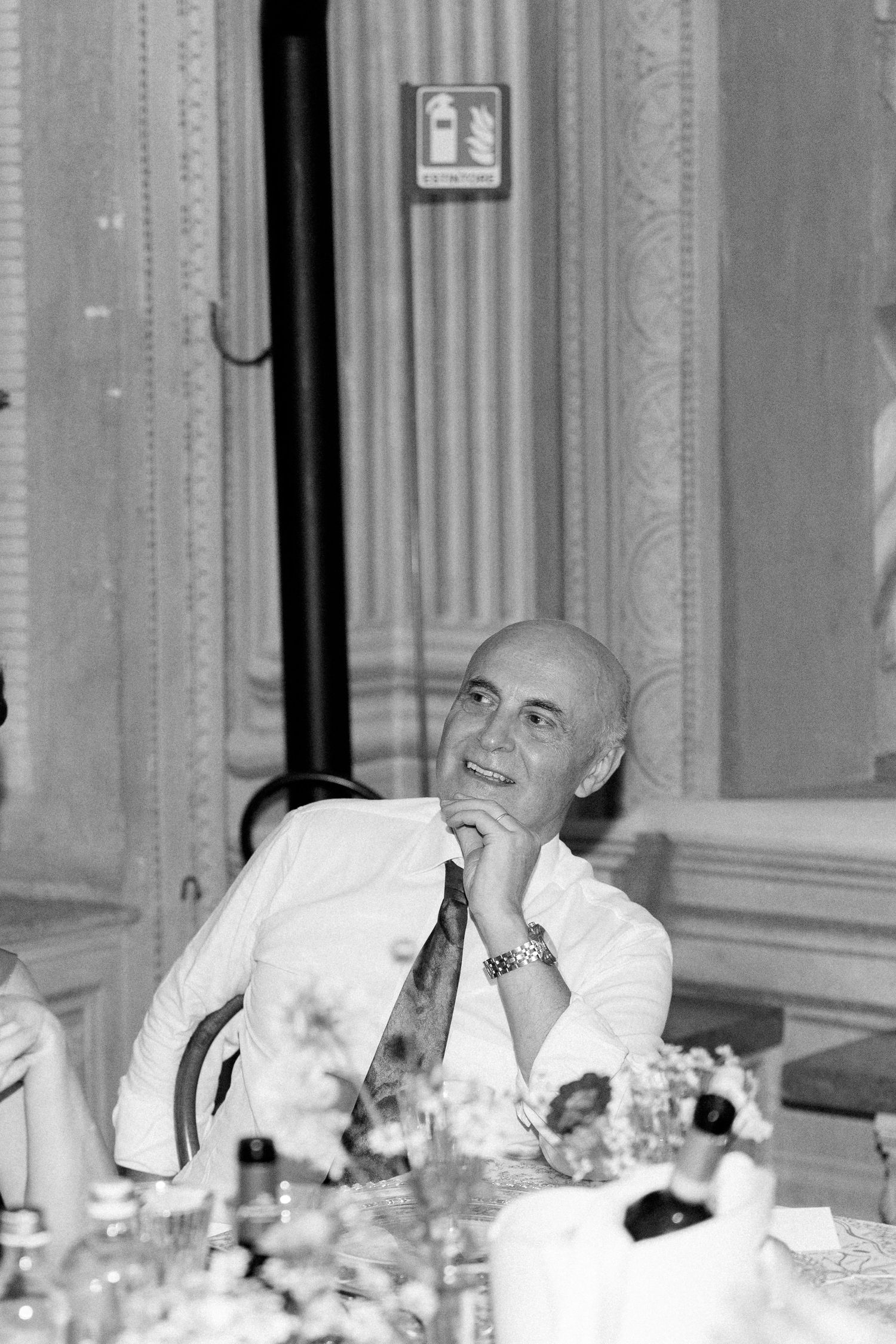 Candid black and white photo of dinner guests laughing at an elegant banquet.