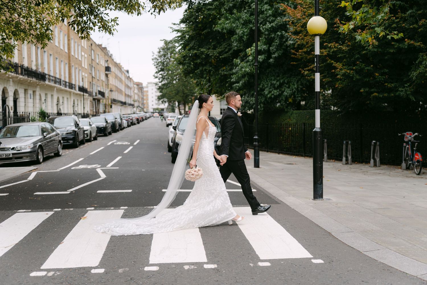 Couple walking across a street crosswalk in wedding attire.