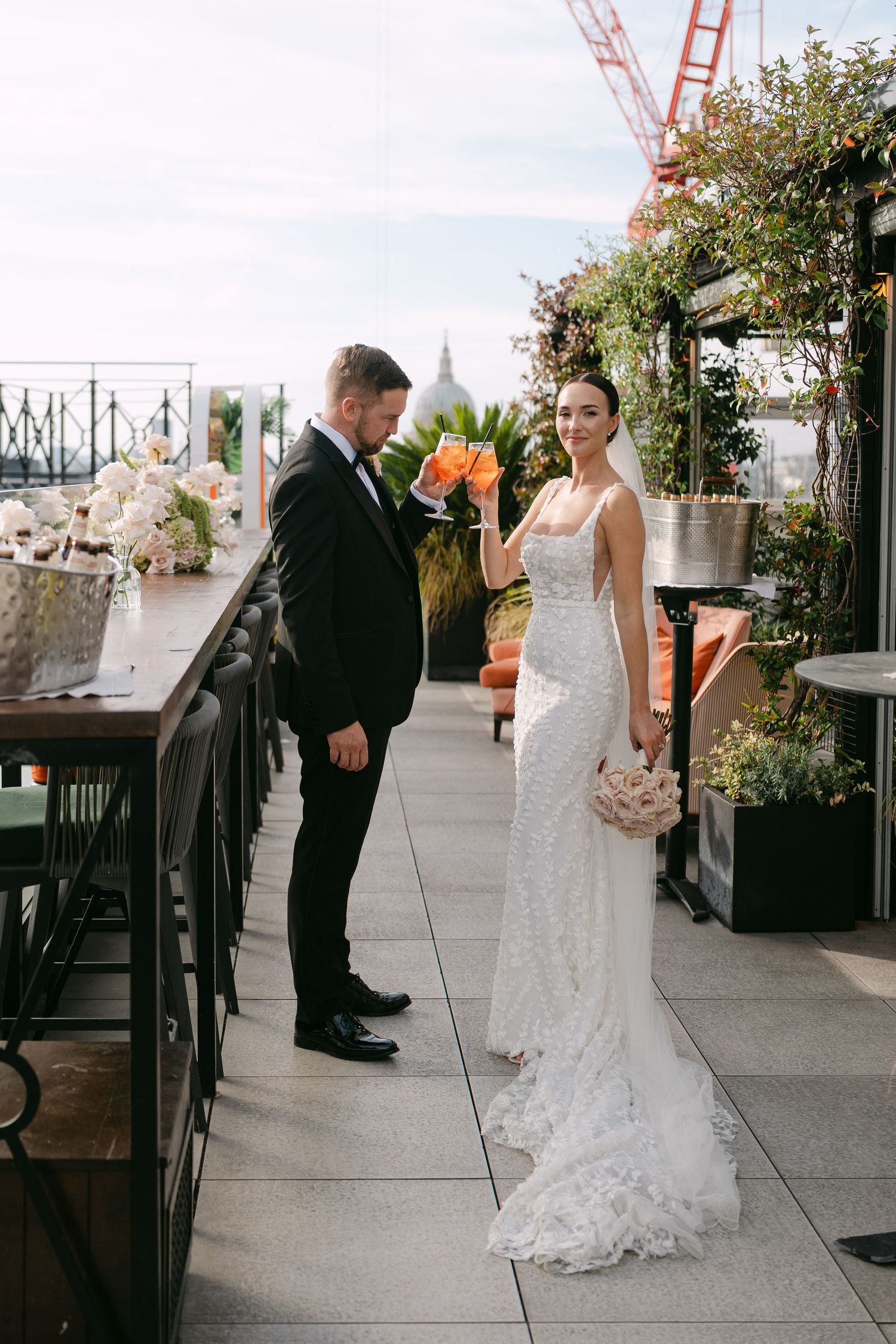 A wedding couple interacts on an outdoor terrace with city views and decorative elements.