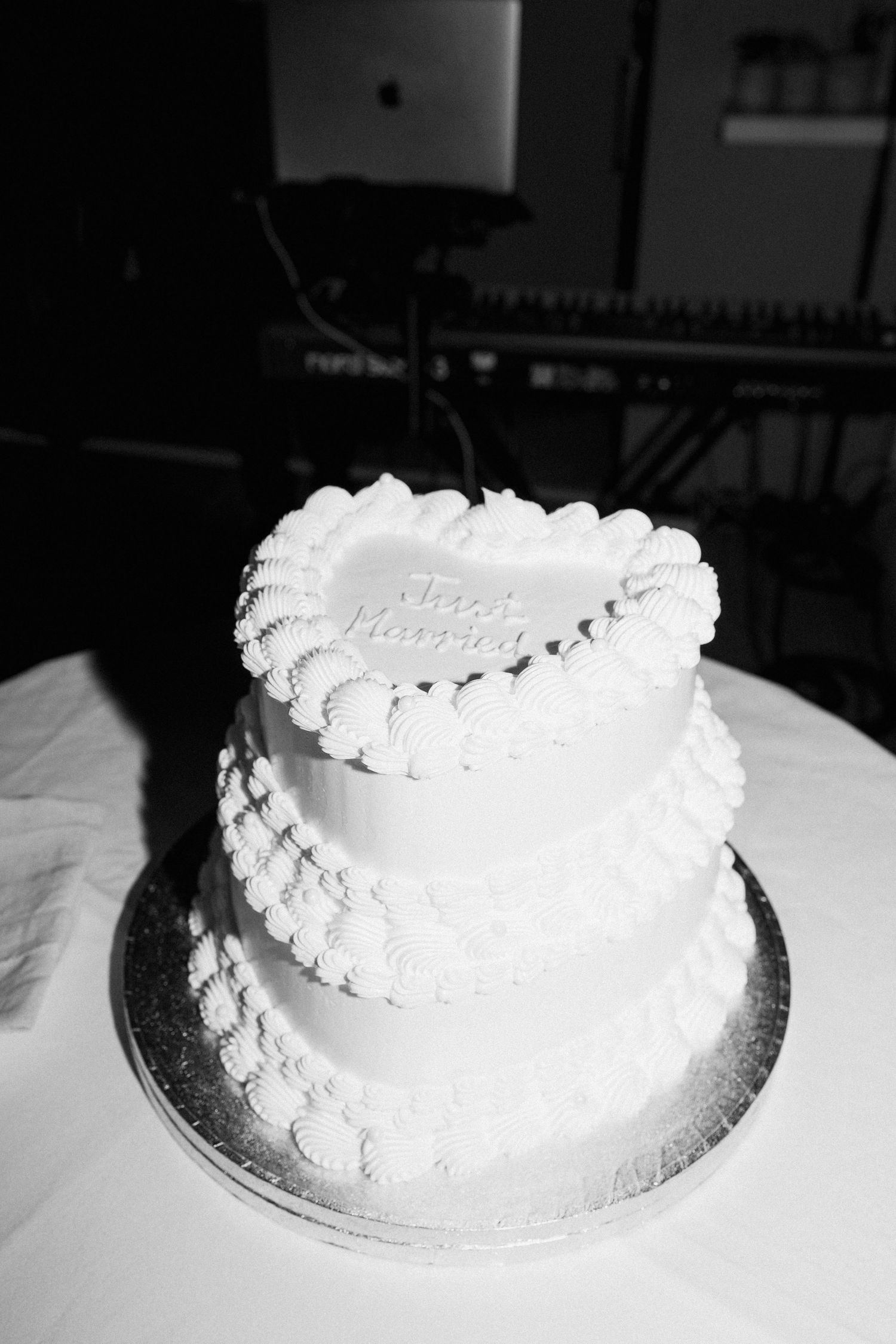 Classic white wedding cake with delicate piped frosting details on a silver cake stand.