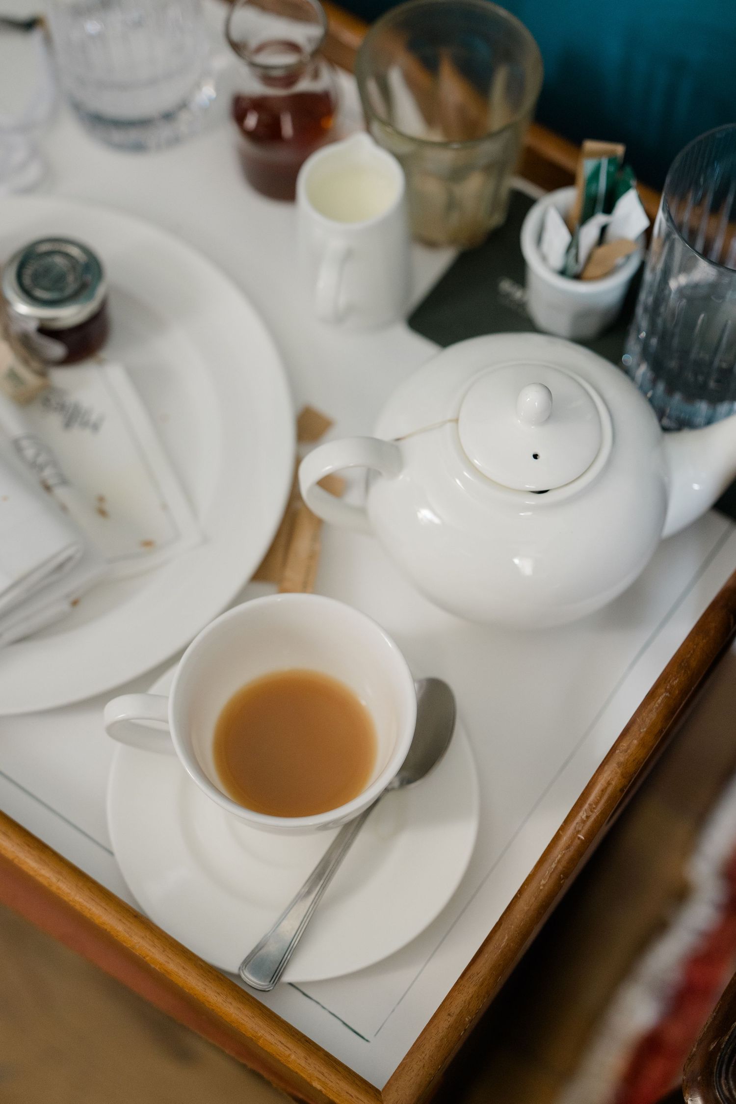 White teapot and cup of tea with milk on a wooden tray at a wedding morning preparation setting.