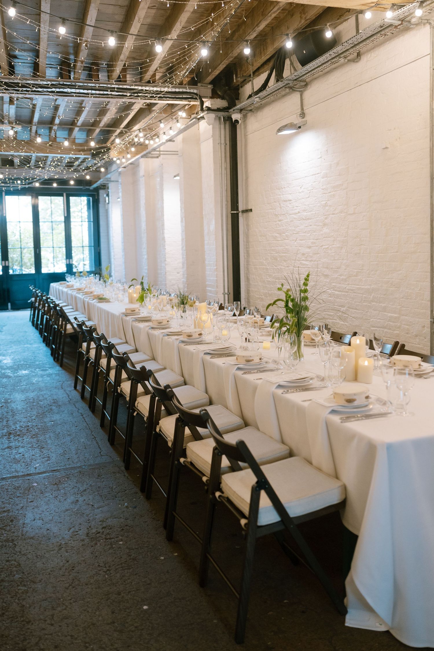 Elegant wedding reception venue with white tablecloths and string lights overhead.