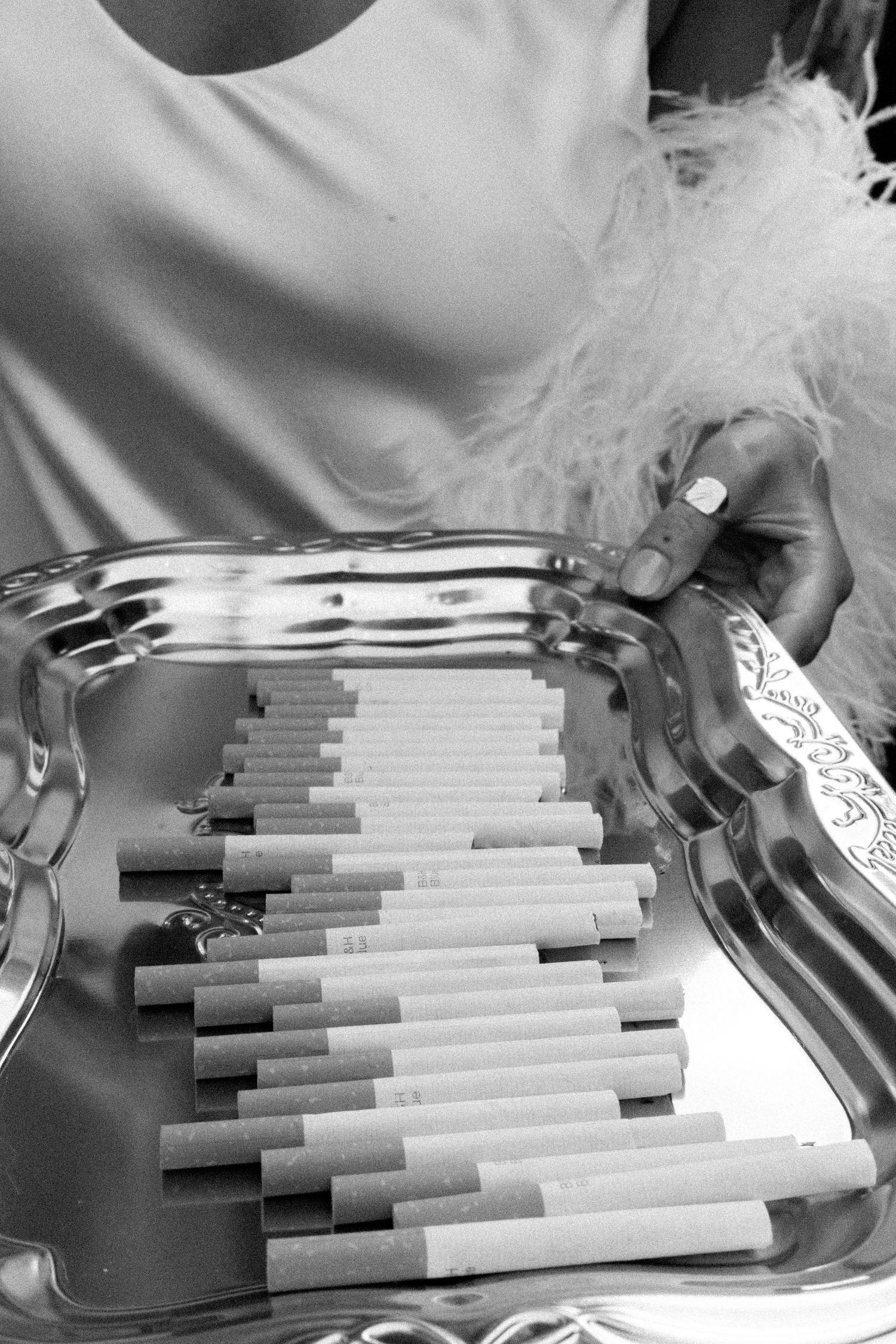 Multiple cigarettes arranged in rows on a silver serving tray at an event.