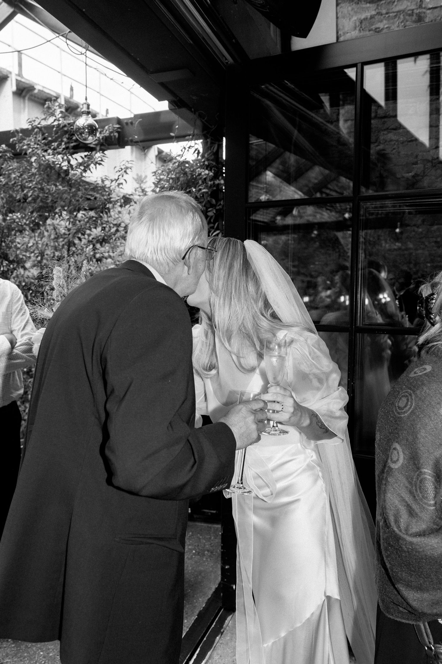 Wedding guests mingling in formal attire under a covered outdoor reception area.