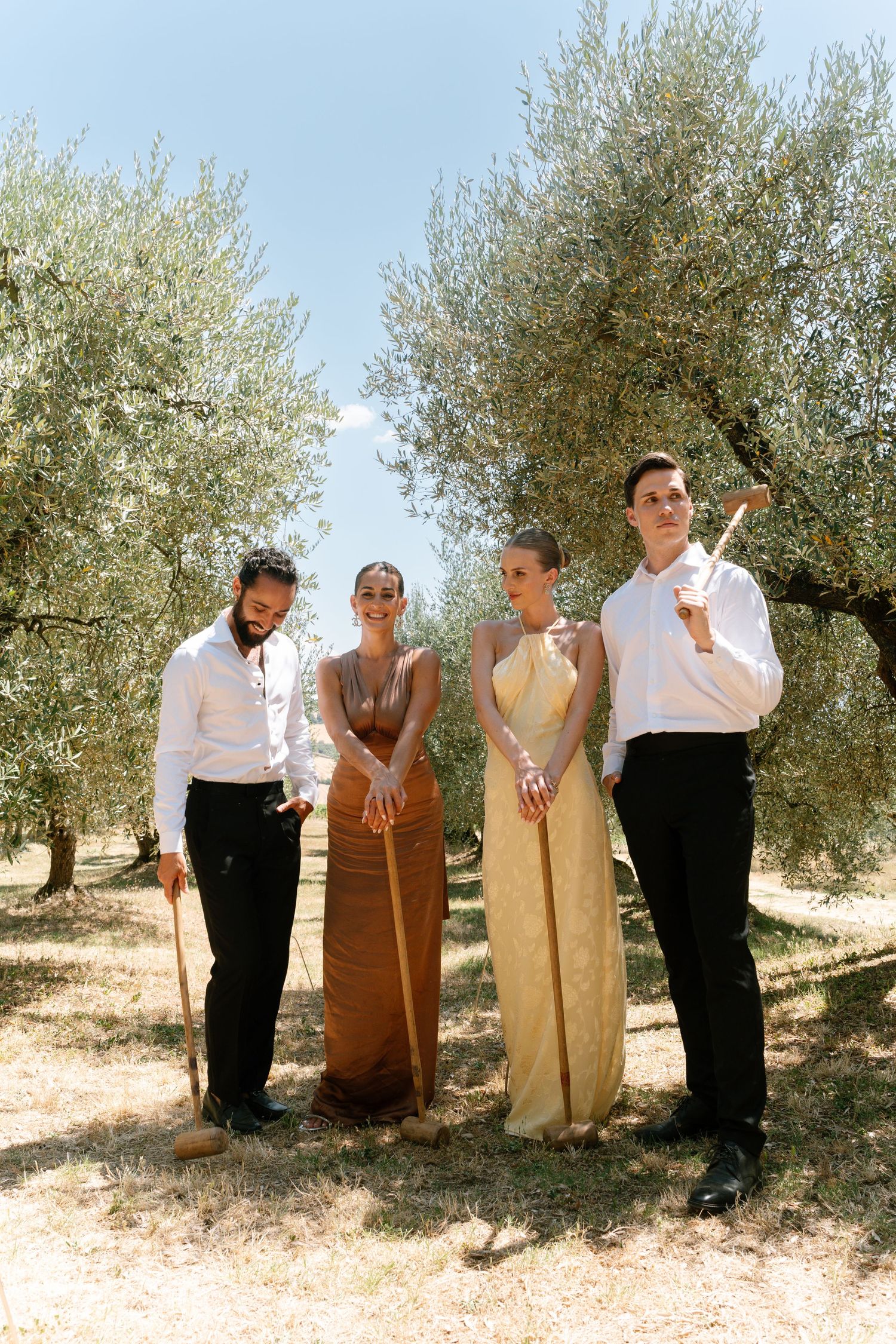 Group standing together under olive trees in casual attire for a relaxed outdoor gathering.