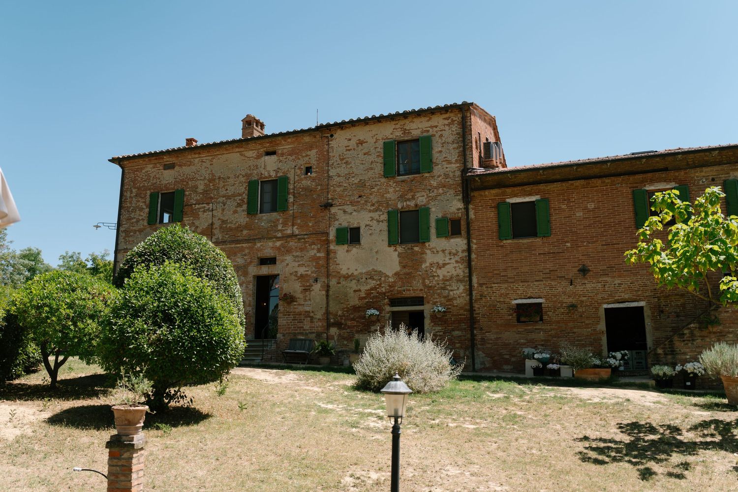 Traditional Tuscan stone farmhouse buildings under bright blue summer sky.
