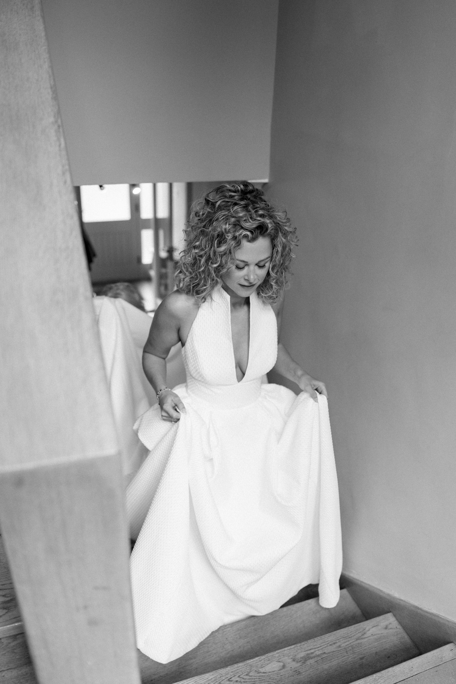 Black and white photos showing someone in a white dress descending stairs.