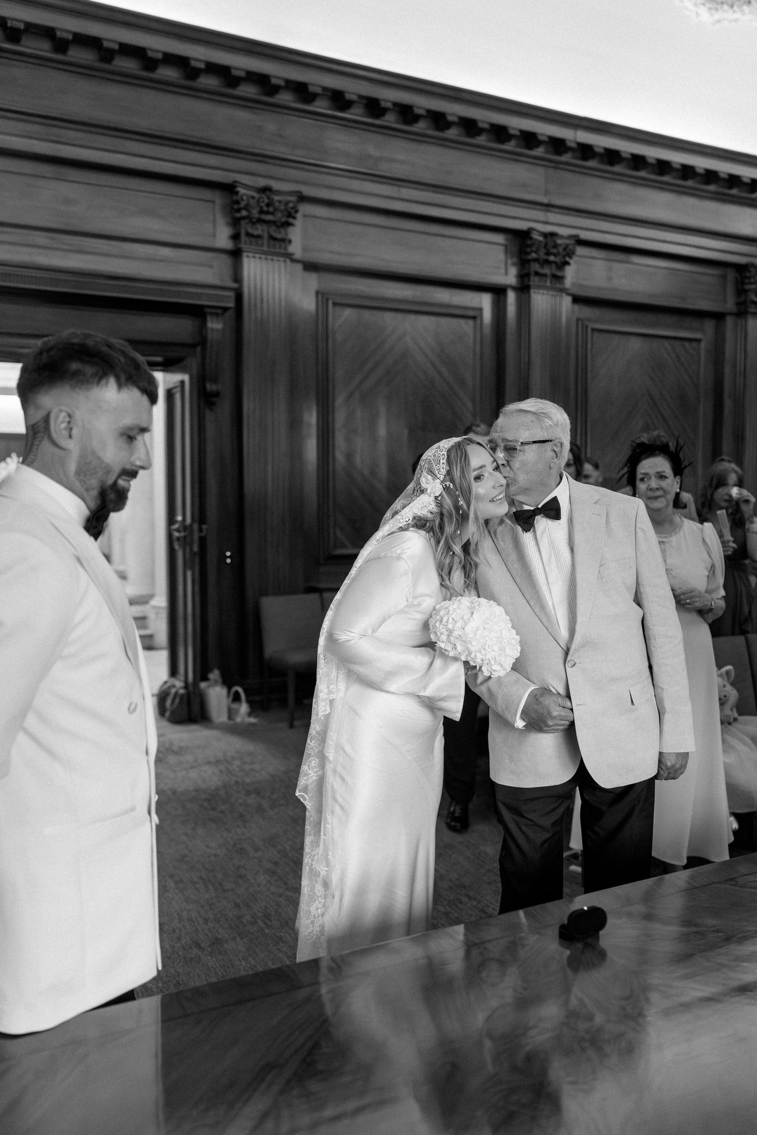 A series of black and white candid wedding moments showing guests dancing and celebrating in an elegant indoor venue.