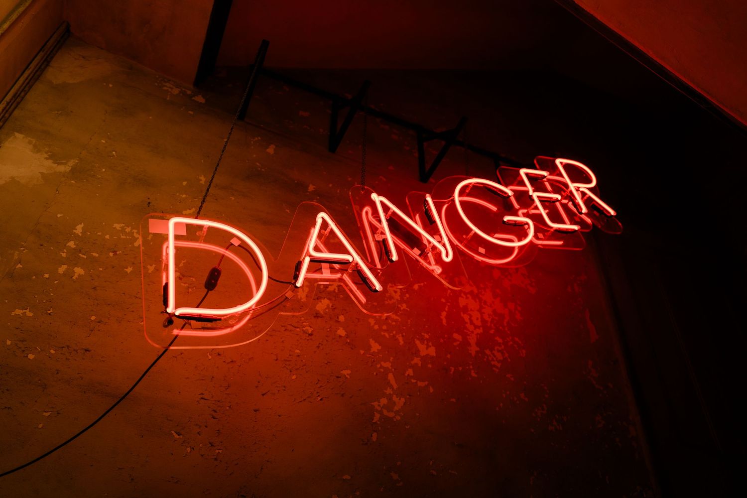 Red neon DANGER sign glowing against a dark concrete wall at a wedding reception.