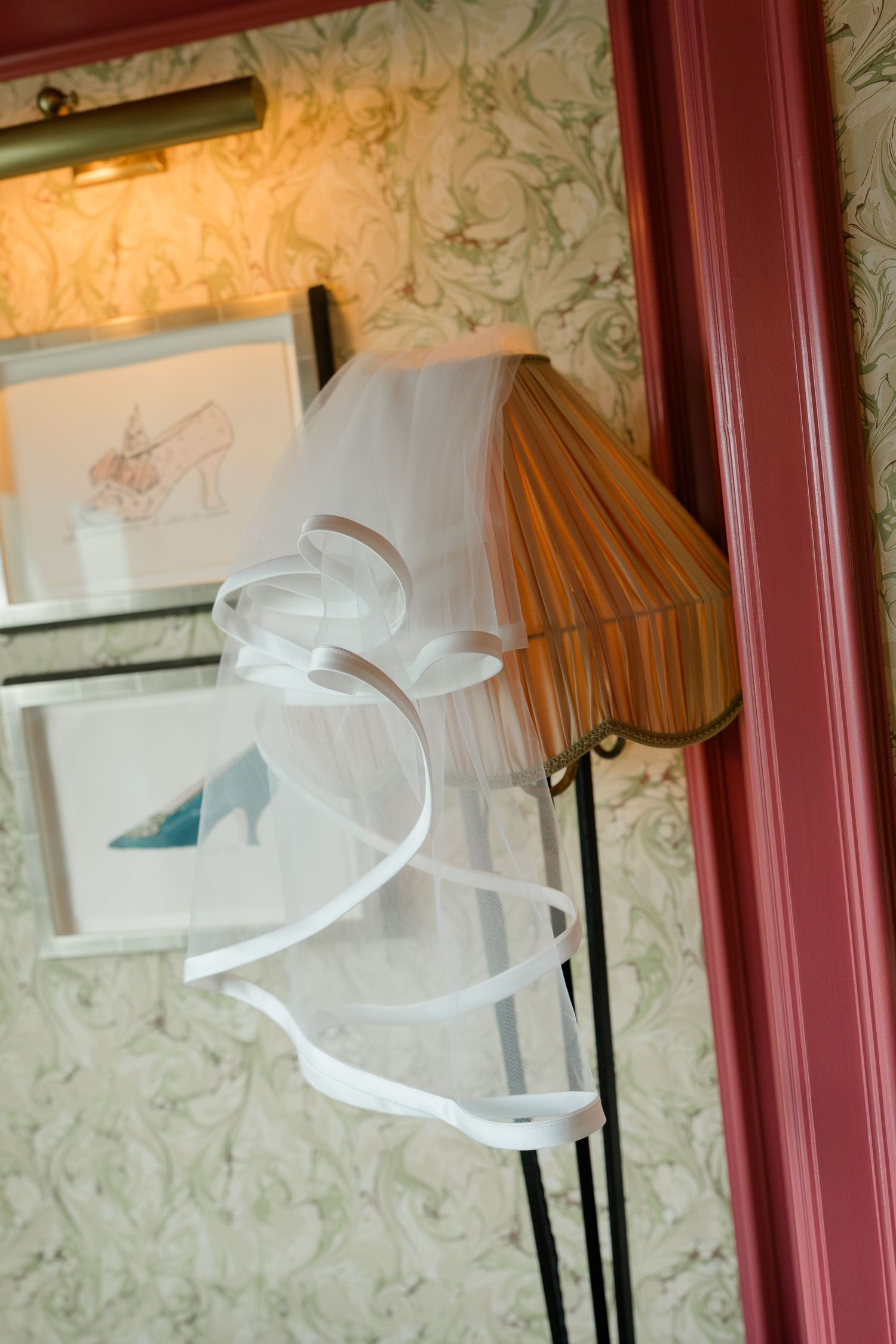 A delicate white bridal veil draped over a striped lamp shade in an elegantly decorated room.