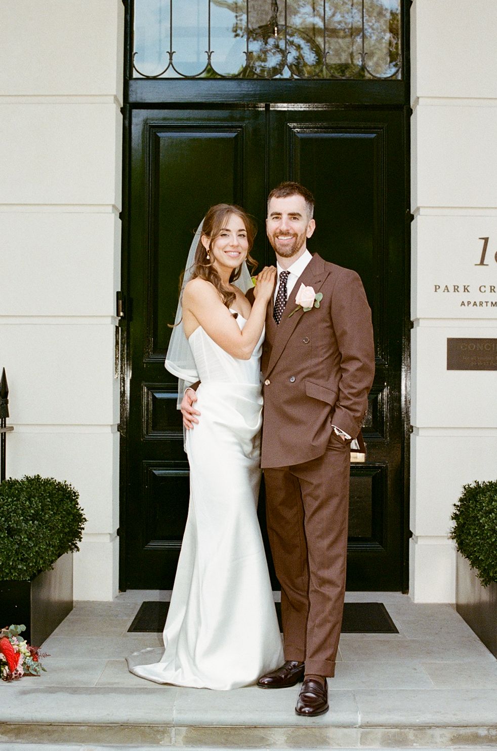 Bride and groom posing in front of black door at Park Crescent Apartments London.