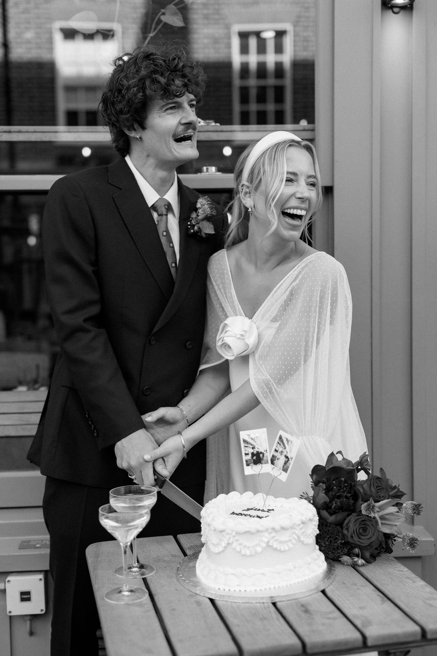 A joyful moment as newlyweds laugh while cutting their wedding cake together.
