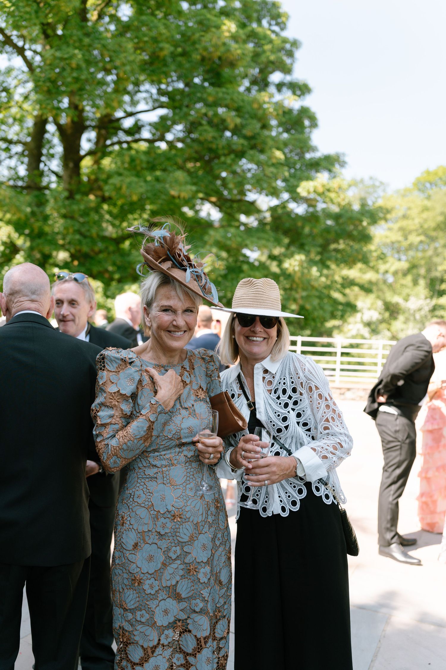 Wedding guests in formal attire sharing joyful moments at an outdoor celebration.
