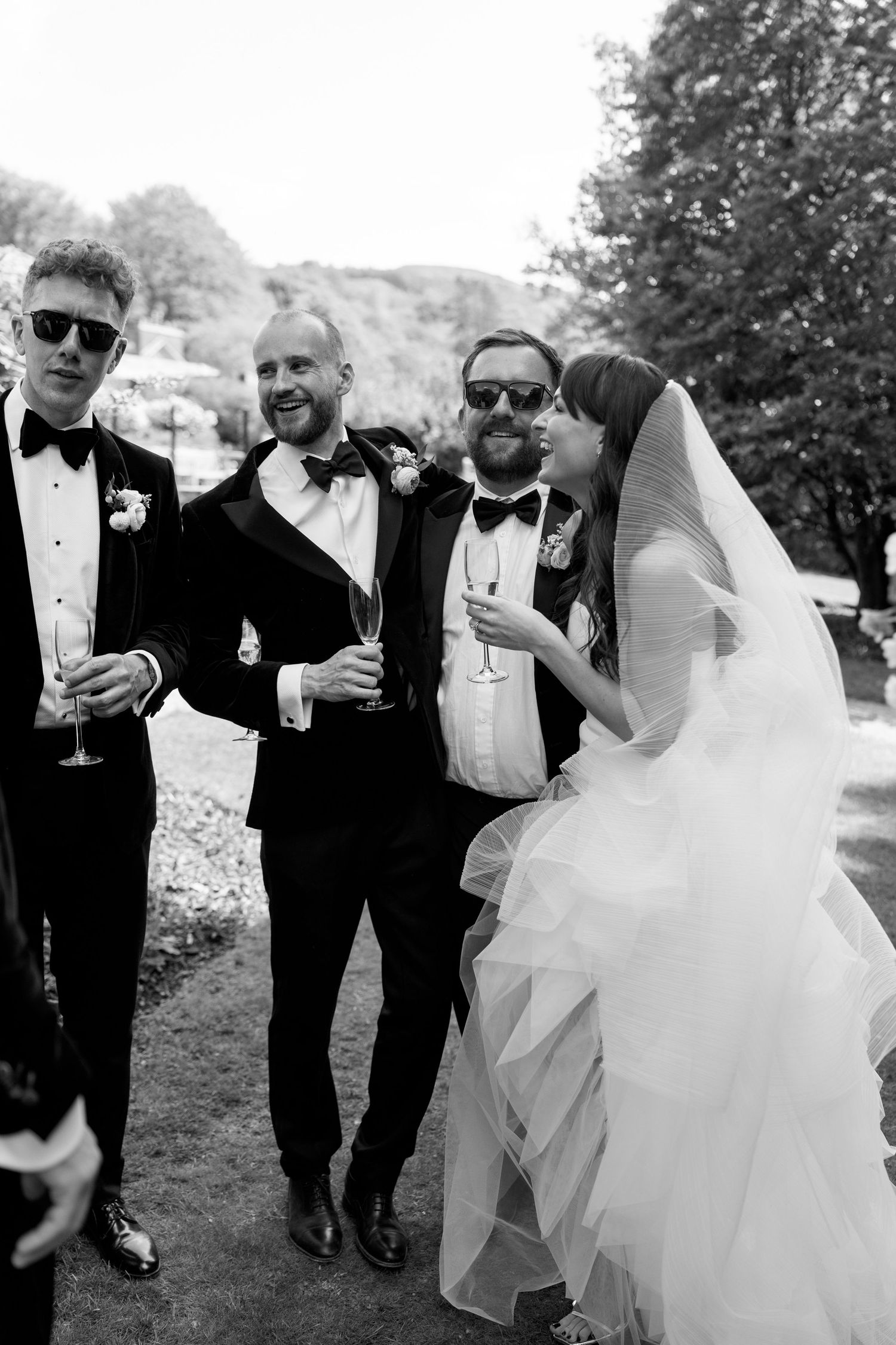 Wedding party walks together sharing drinks and laughter on a sunny afternoon.