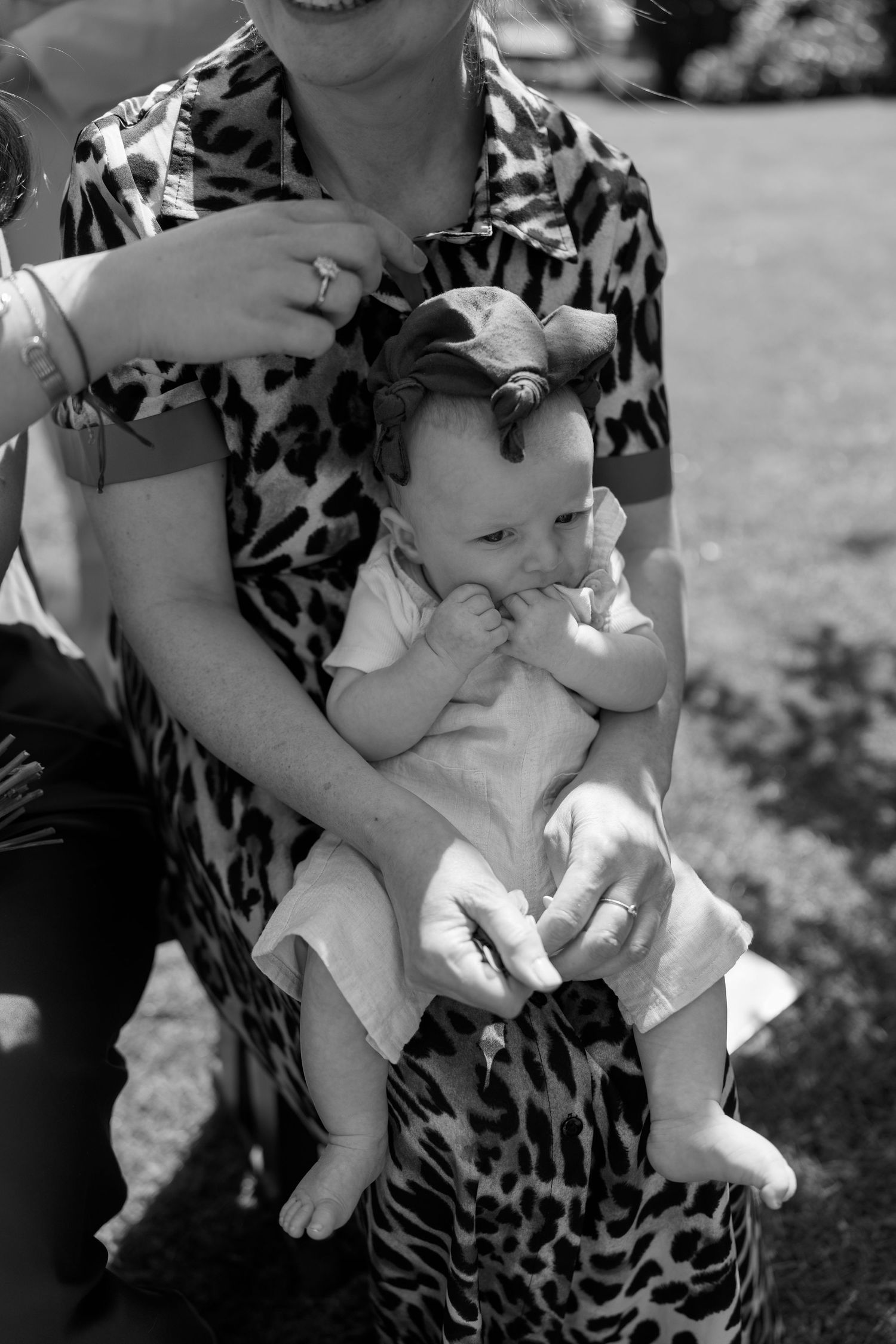 Black and white photo series showing a small baby being held during an outdoor event.