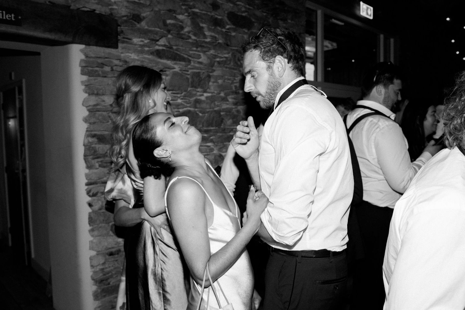 Wedding guests dance and laugh together on the reception dance floor.