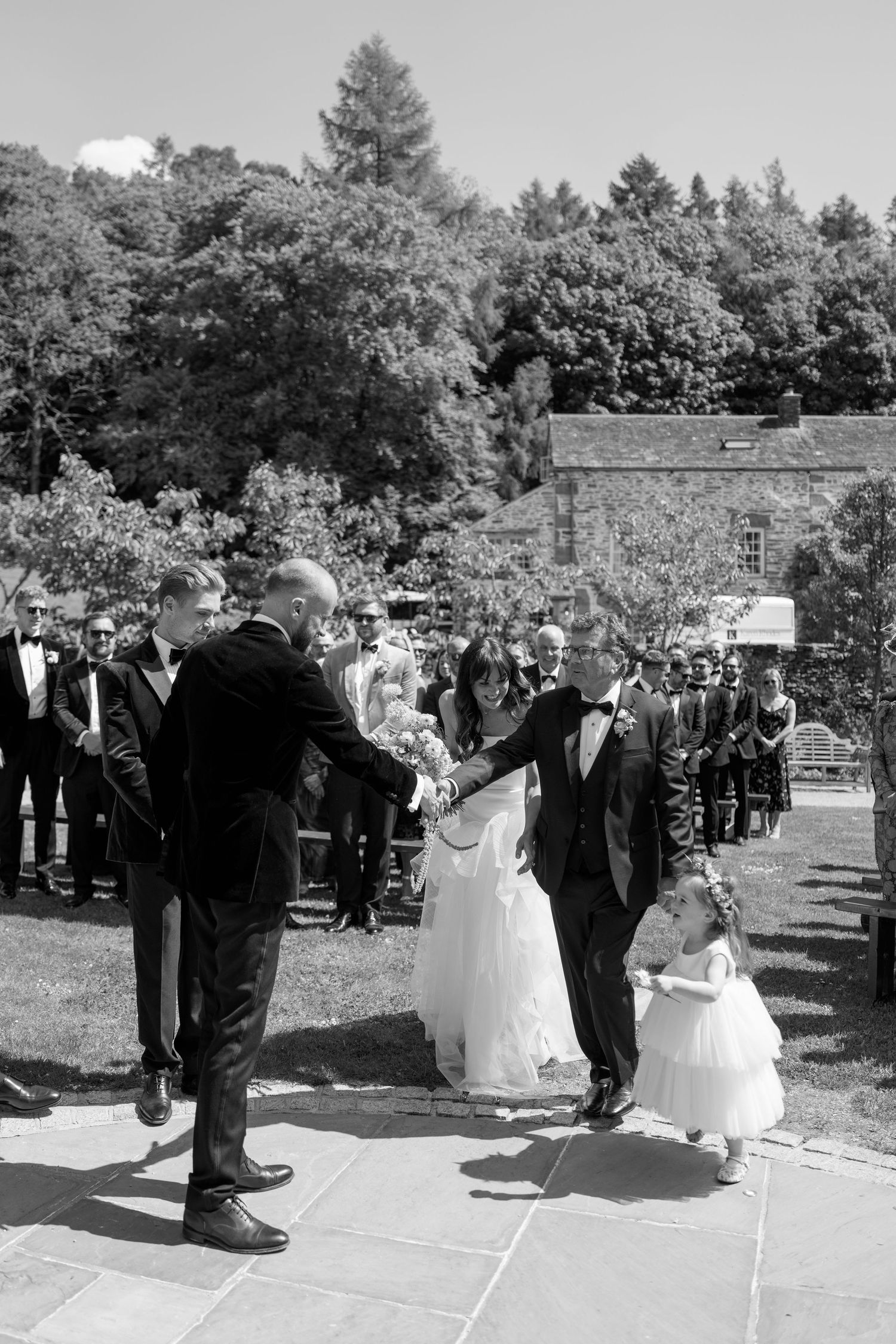 Black and white wedding ceremony procession on outdoor stone patio.