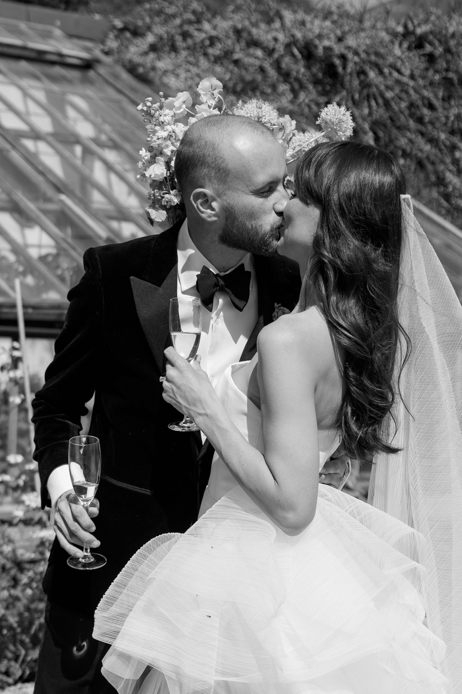 A romantic black and white photo of a couple sharing an intimate moment in a garden.