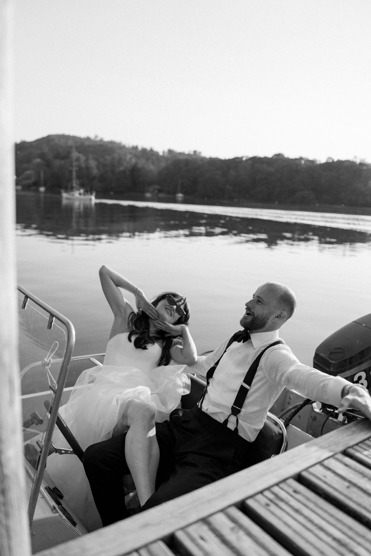 Three people relaxing in white chairs on a boat while cruising across a peaceful lake.