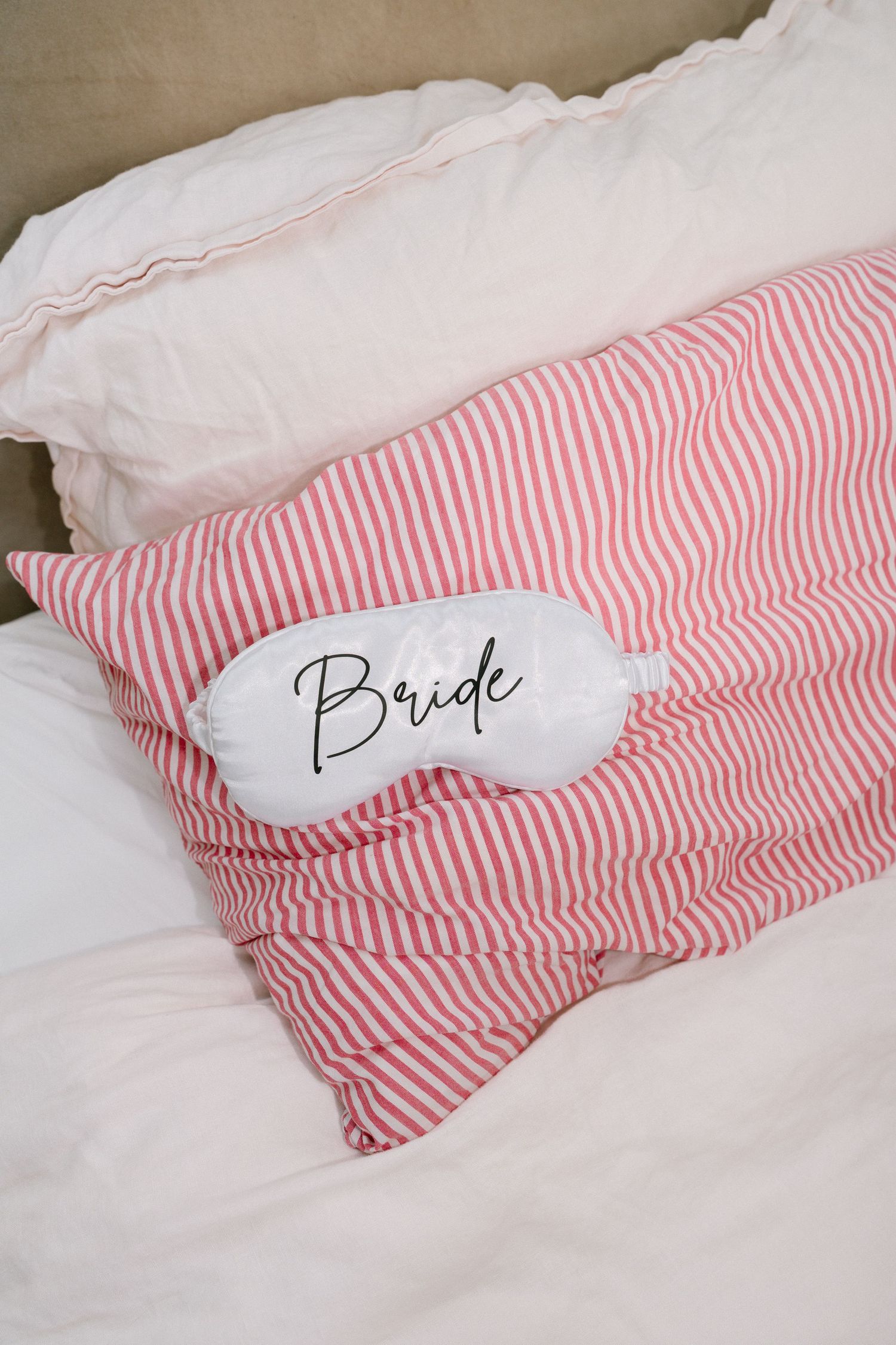 Pink and white striped pillows with text embroidered on white sleep masks.