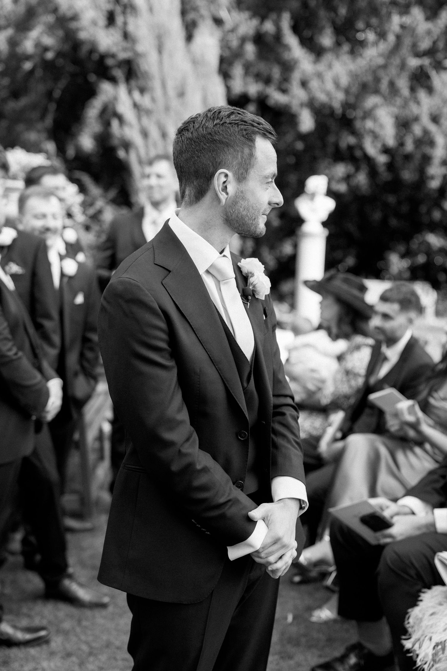 Black and white photo of wedding guests seated on lawn during ceremony.