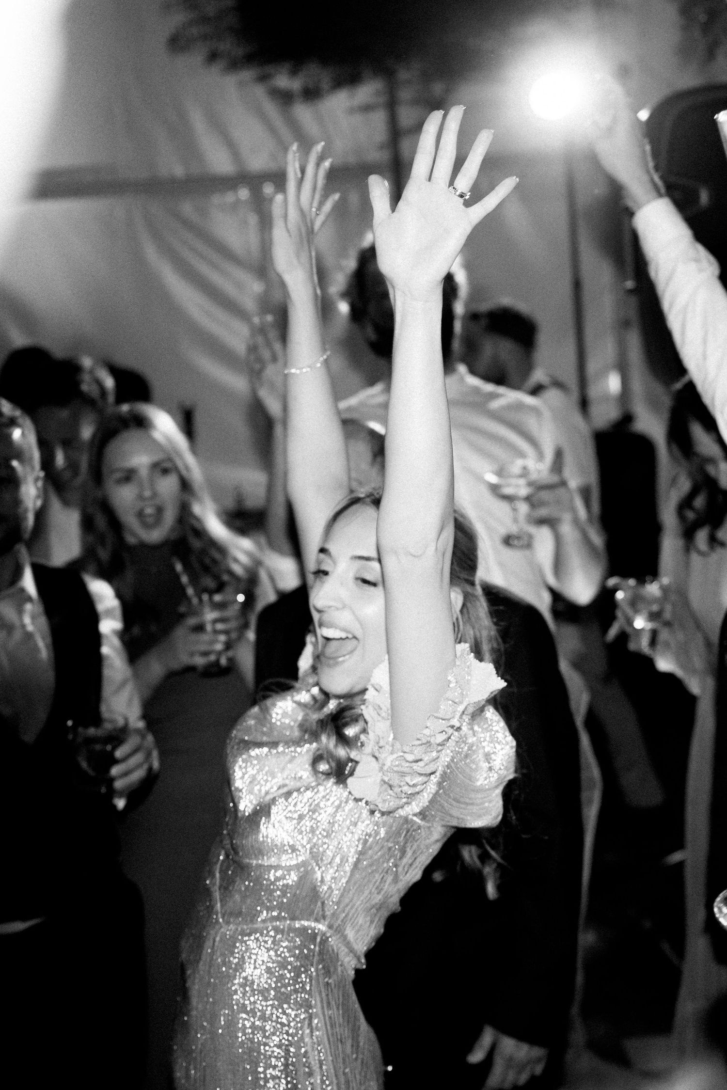 People dancing and raising hands on a dimly lit dance floor.