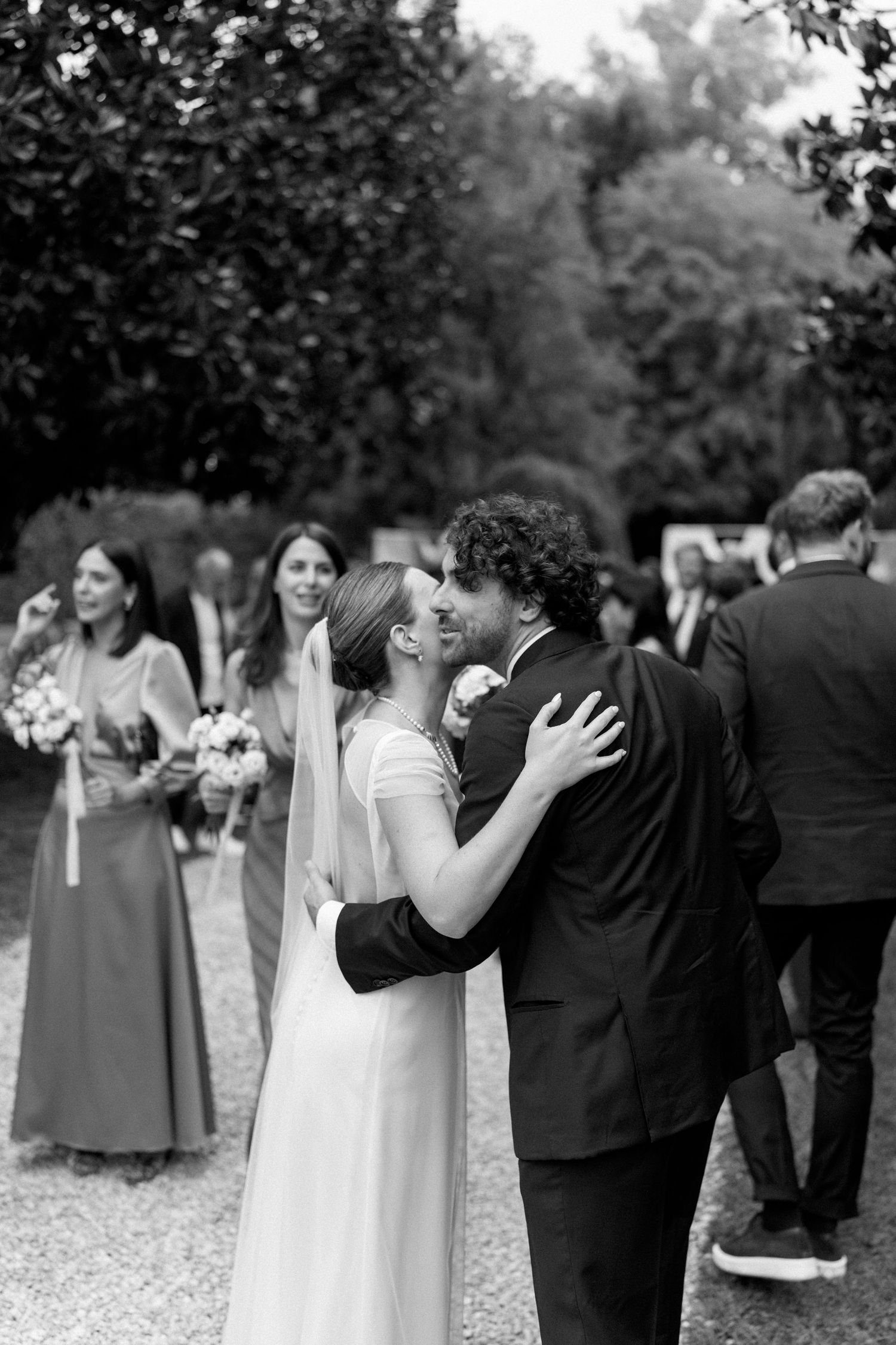 A series of romantic black and white wedding photos showing tender moments between couples during an outdoor celebration.