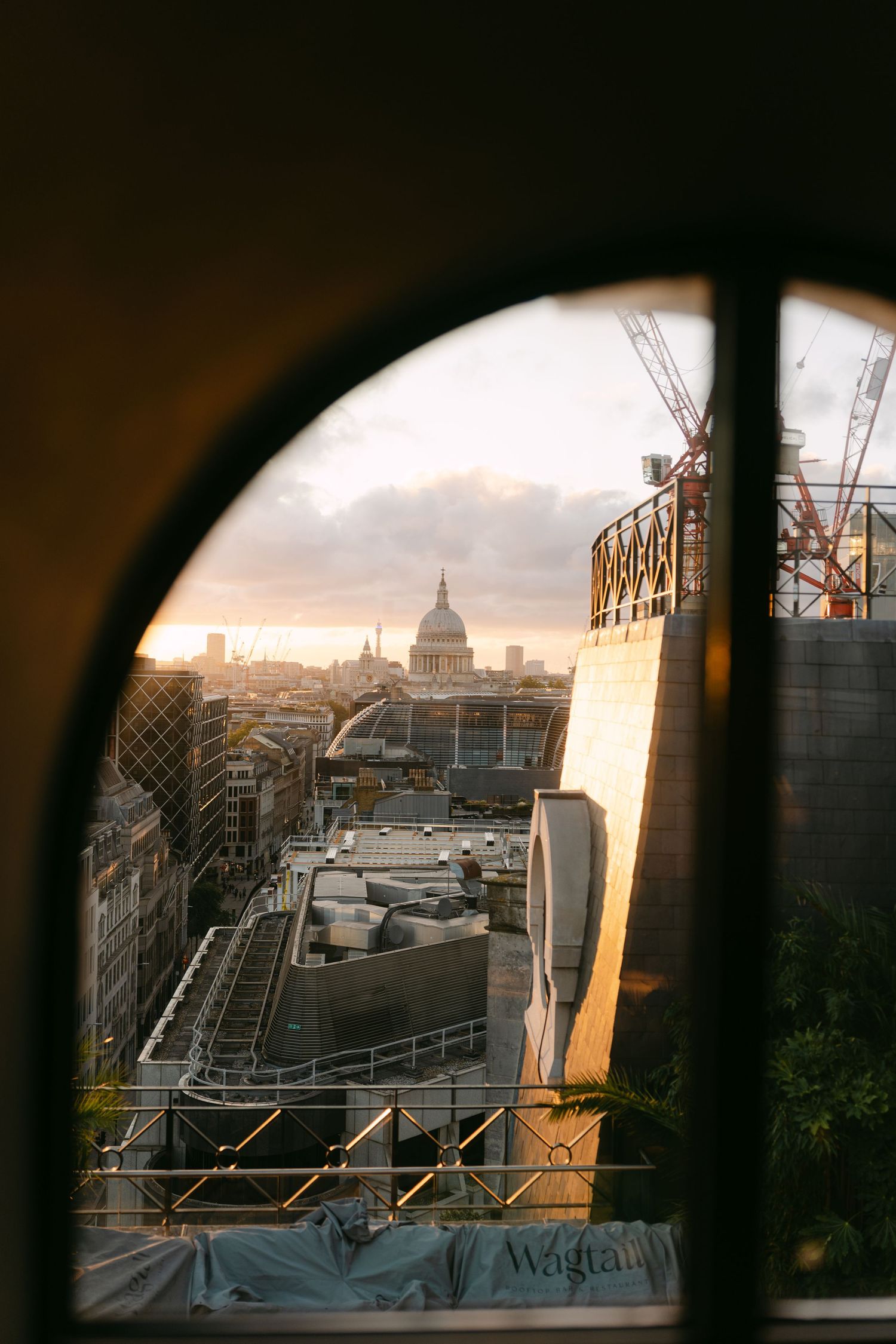 View of St Paul's Cathedral through an arched window during golden hour in London.