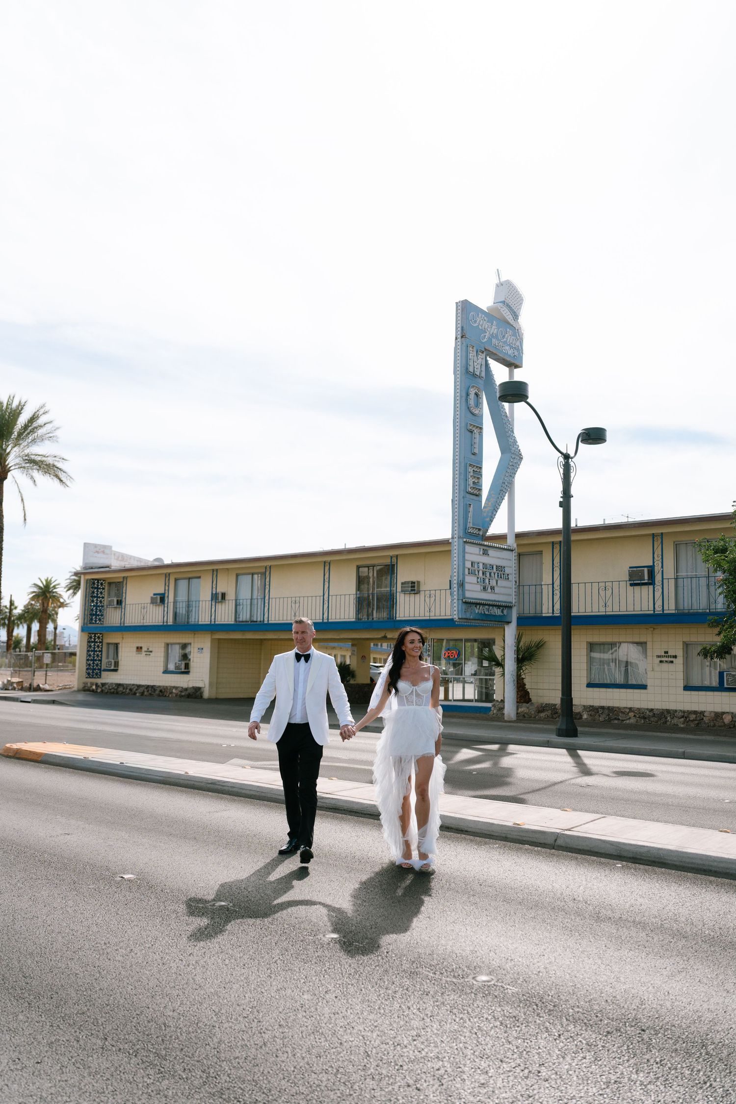 A couple walks along a palm-lined street outside a vintage Las Vegas motel.