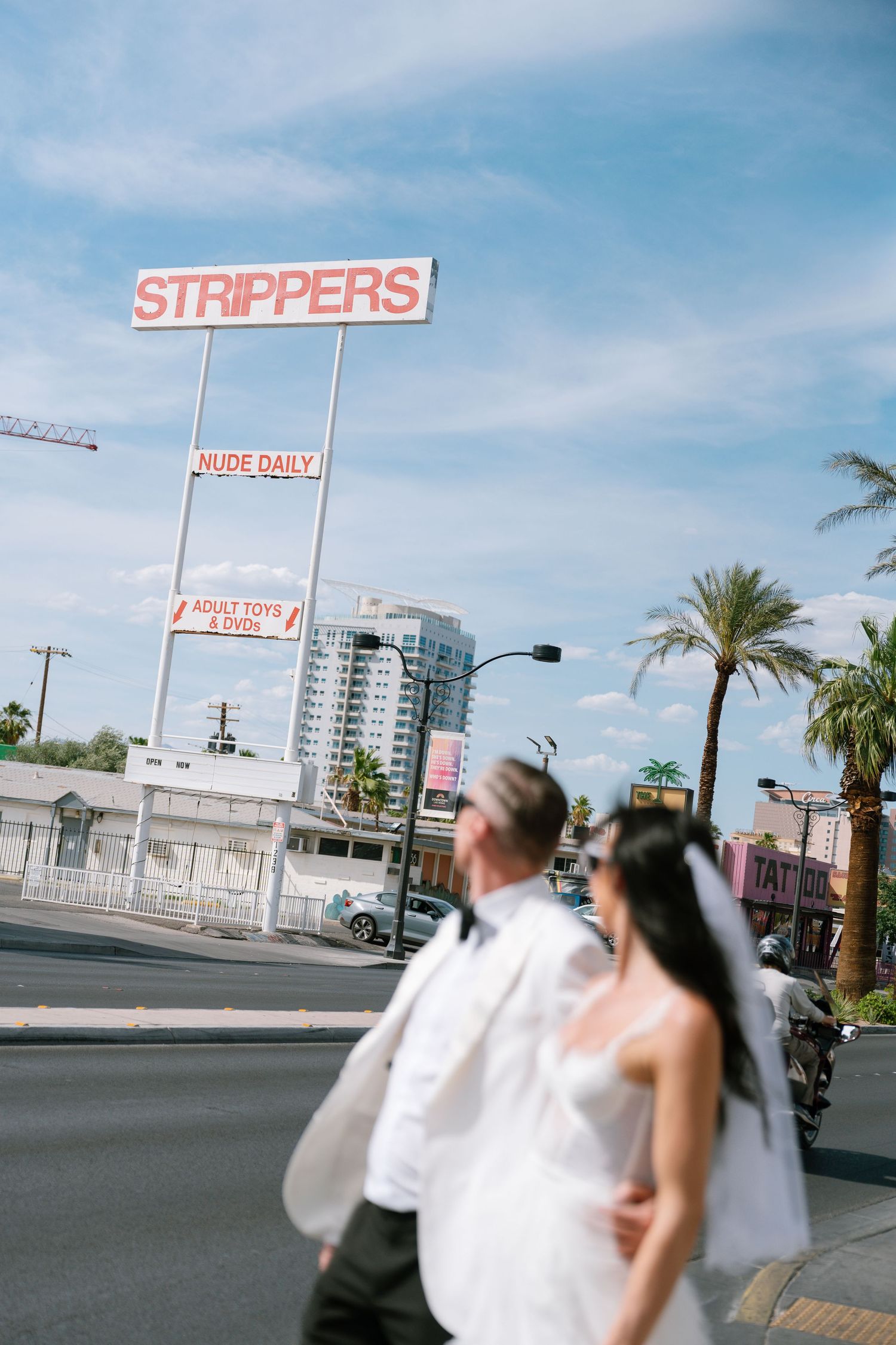 A wedding photoshoot on a Las Vegas street with palm trees and neon signs.