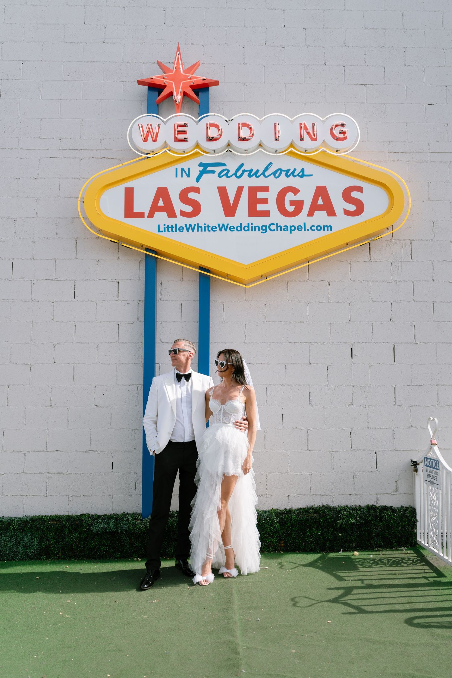 A couple poses beneath iconic Las Vegas welcome signs and wedding chapel signage.
