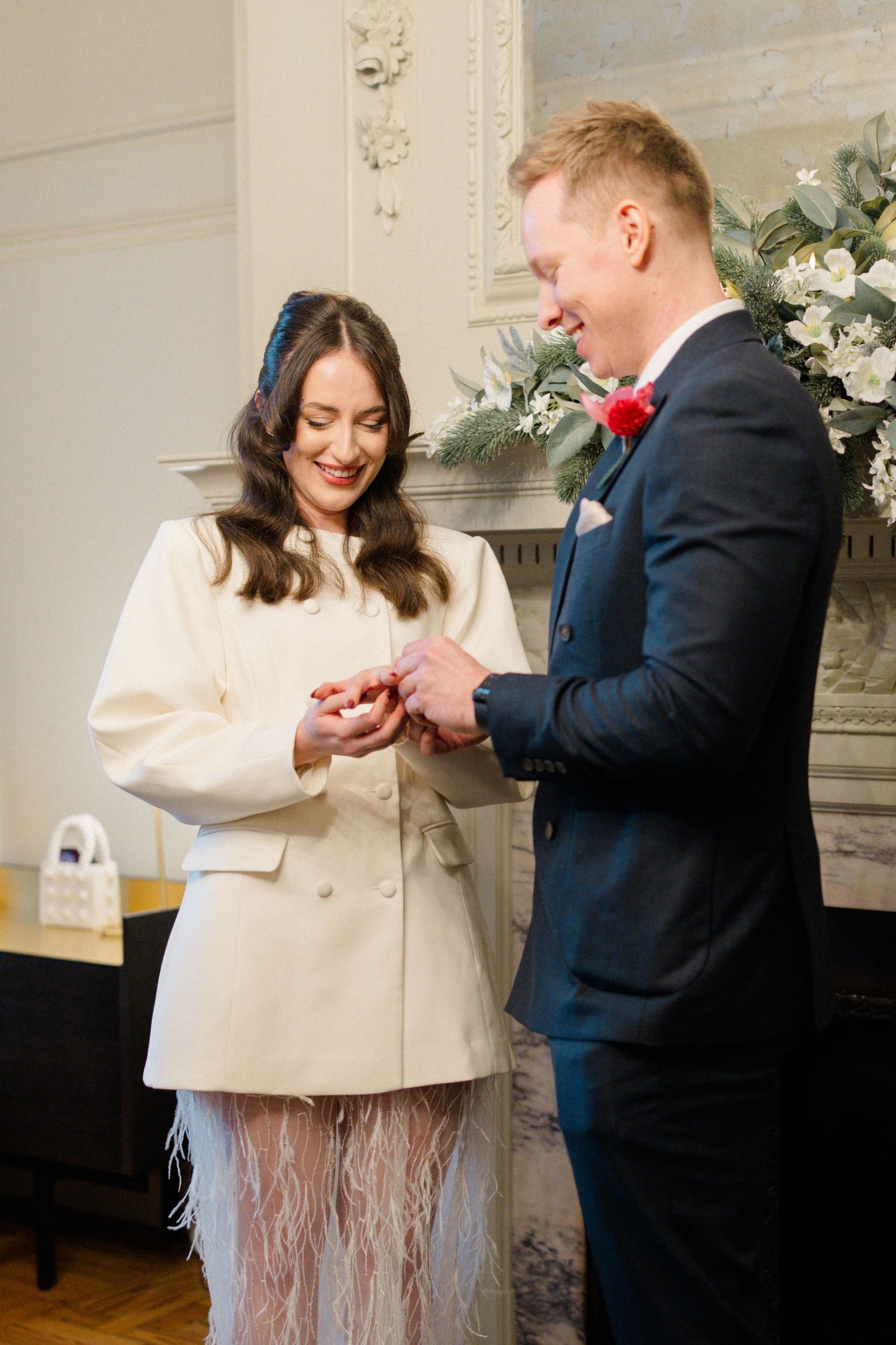 Groom placing wedding ring on brides finger during intimate ceremony at registry office.