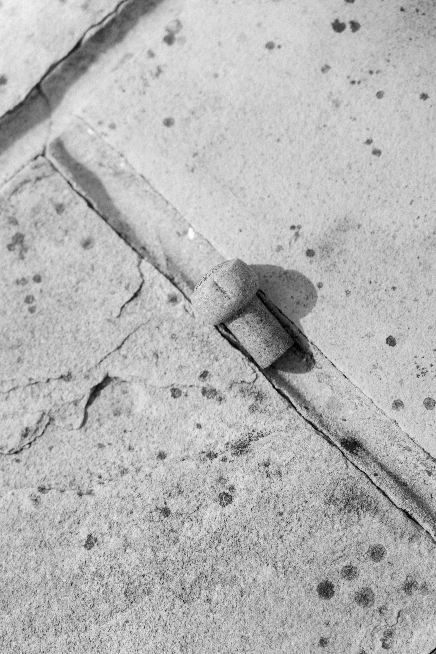 Black and white close-up of a musical note symbol cast as a shadow on concrete.