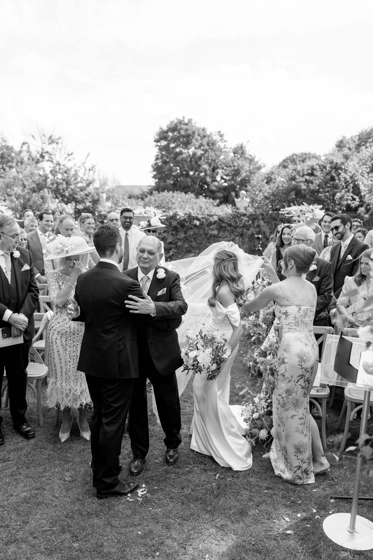 Wedding party and guests mingling during an outdoor garden celebration.