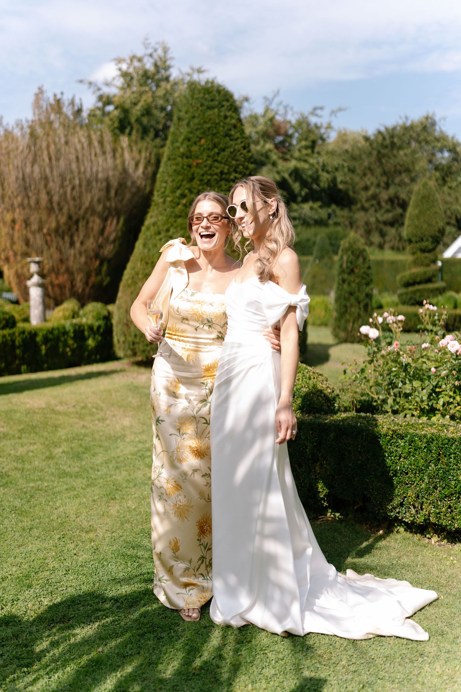 Two people share a joyful moment on a sunny lawn during a wedding celebration.