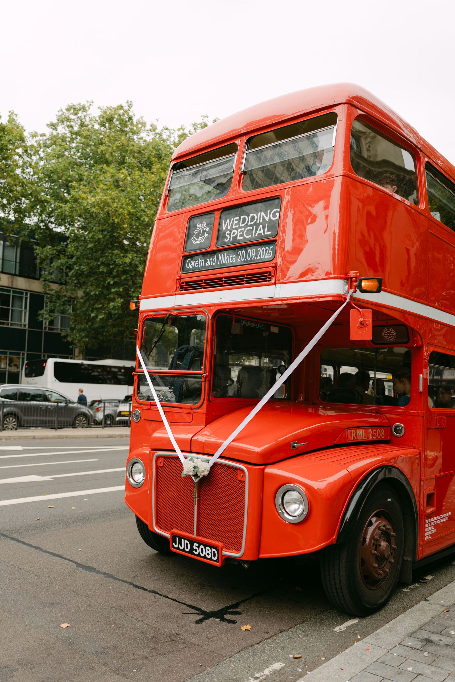 Vintage red double-decker bus with 'Wedding Special' sign parked on urban street.