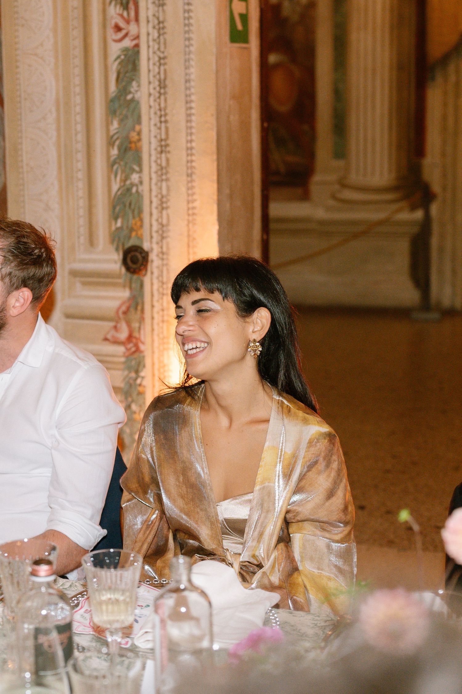 Guests enjoying lively conversation at an ornate banquet table with classical architecture.