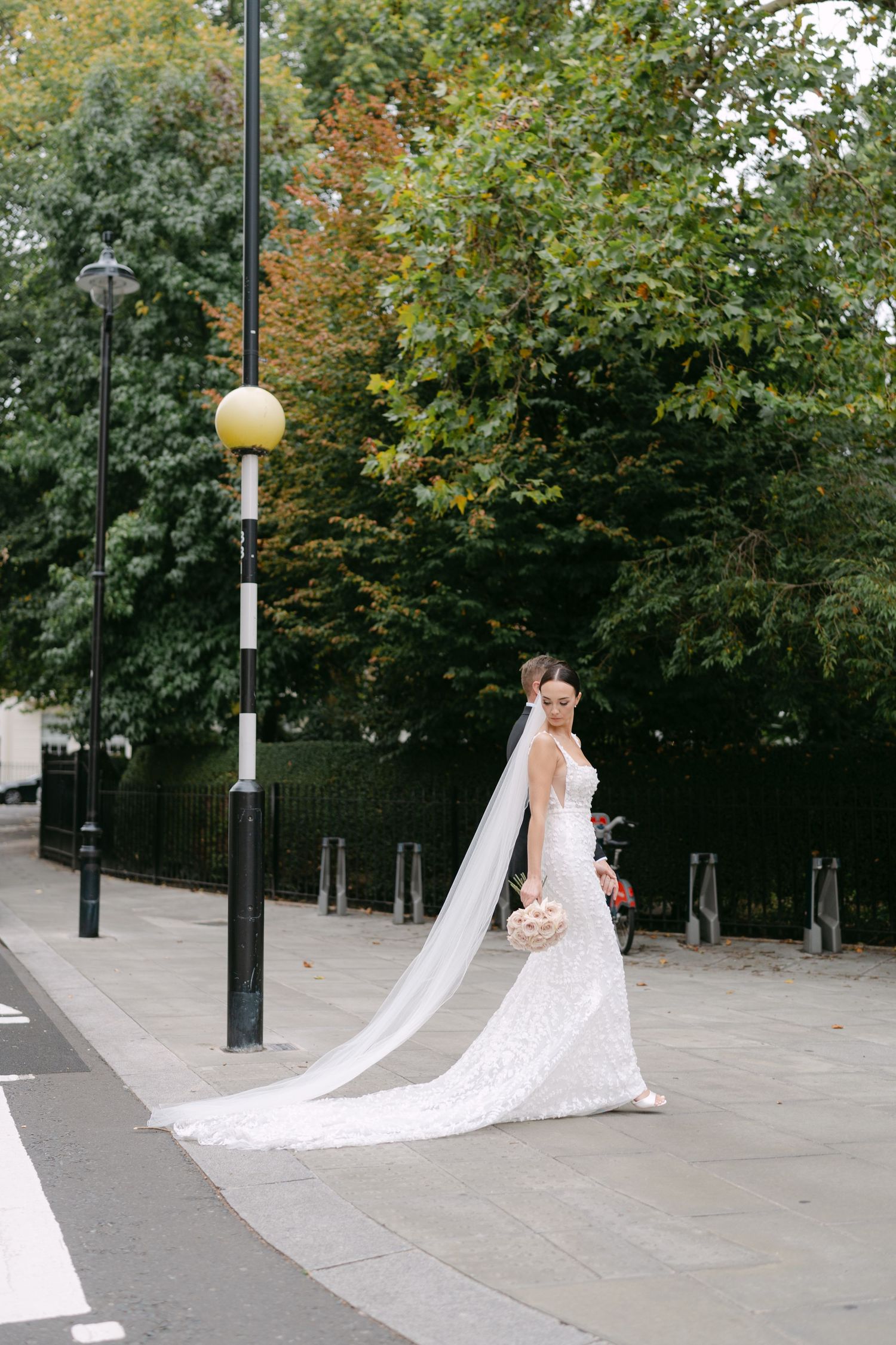 Wedding dress with flowing train photographed in a scenic park setting.