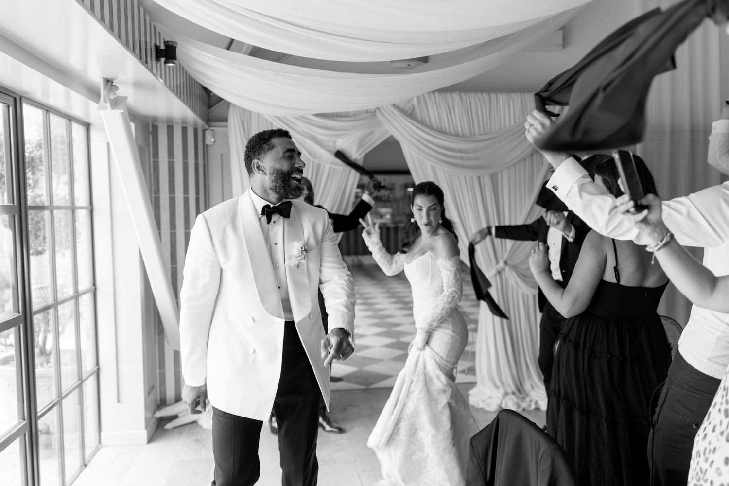 A bride and groom make their grand entrance through a celebratory tunnel at their wedding reception.
