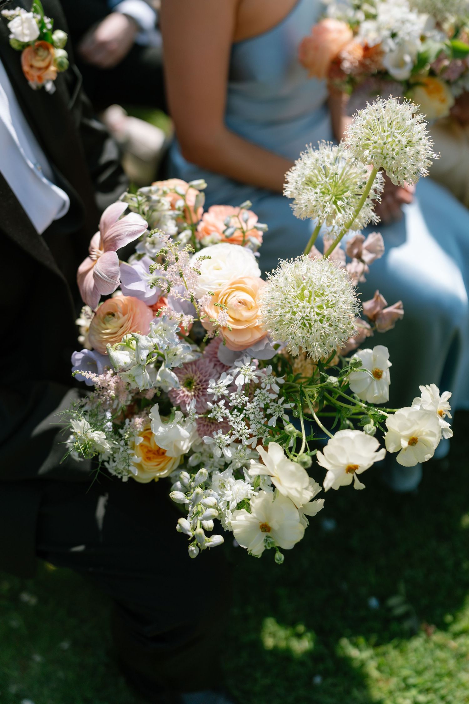 Delicate bouquets featuring peach roses, white flowers, and baby's breath arranged for a wedding.