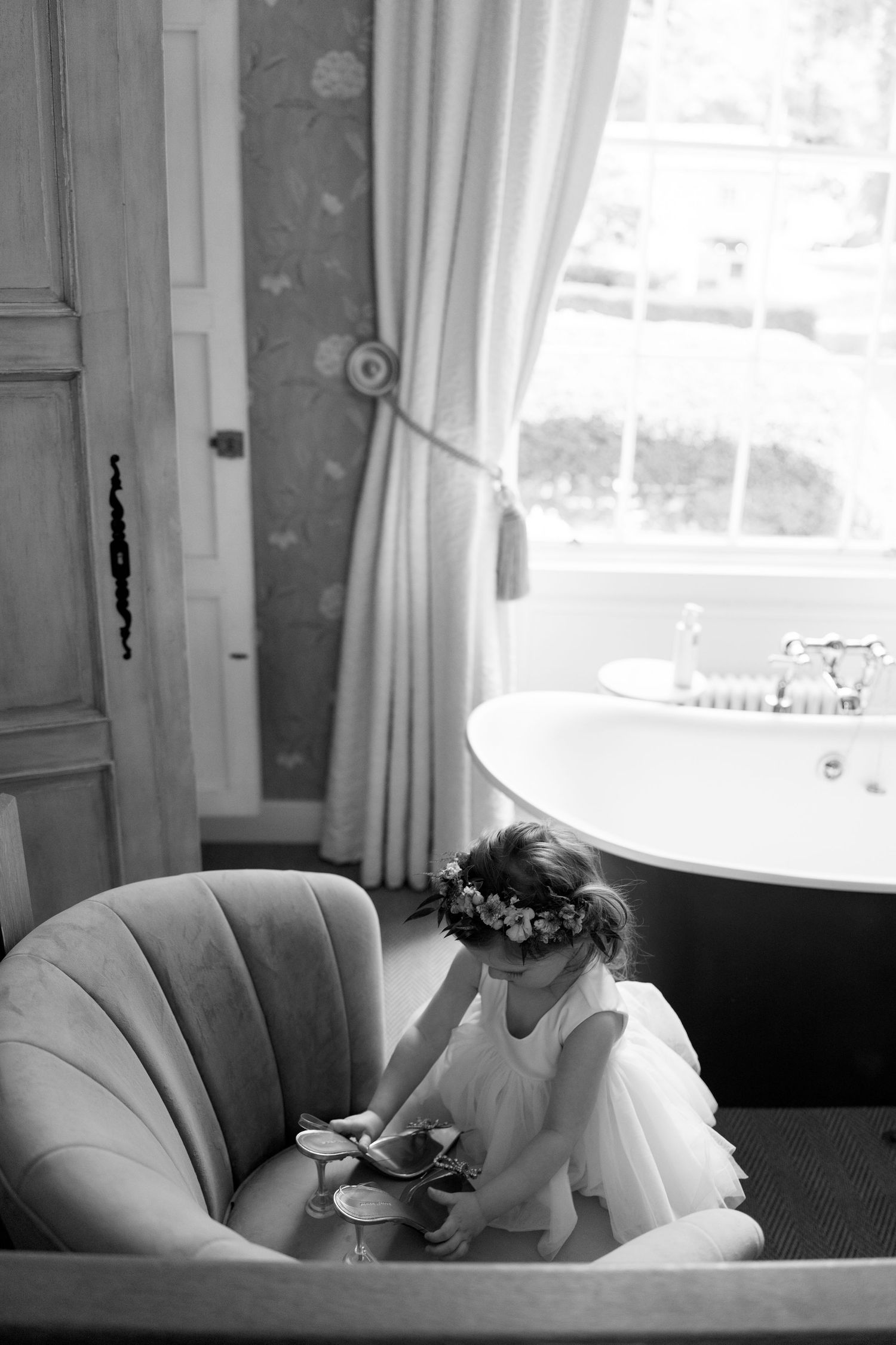 Person in white robe resting on curved couch near window in elegant room.